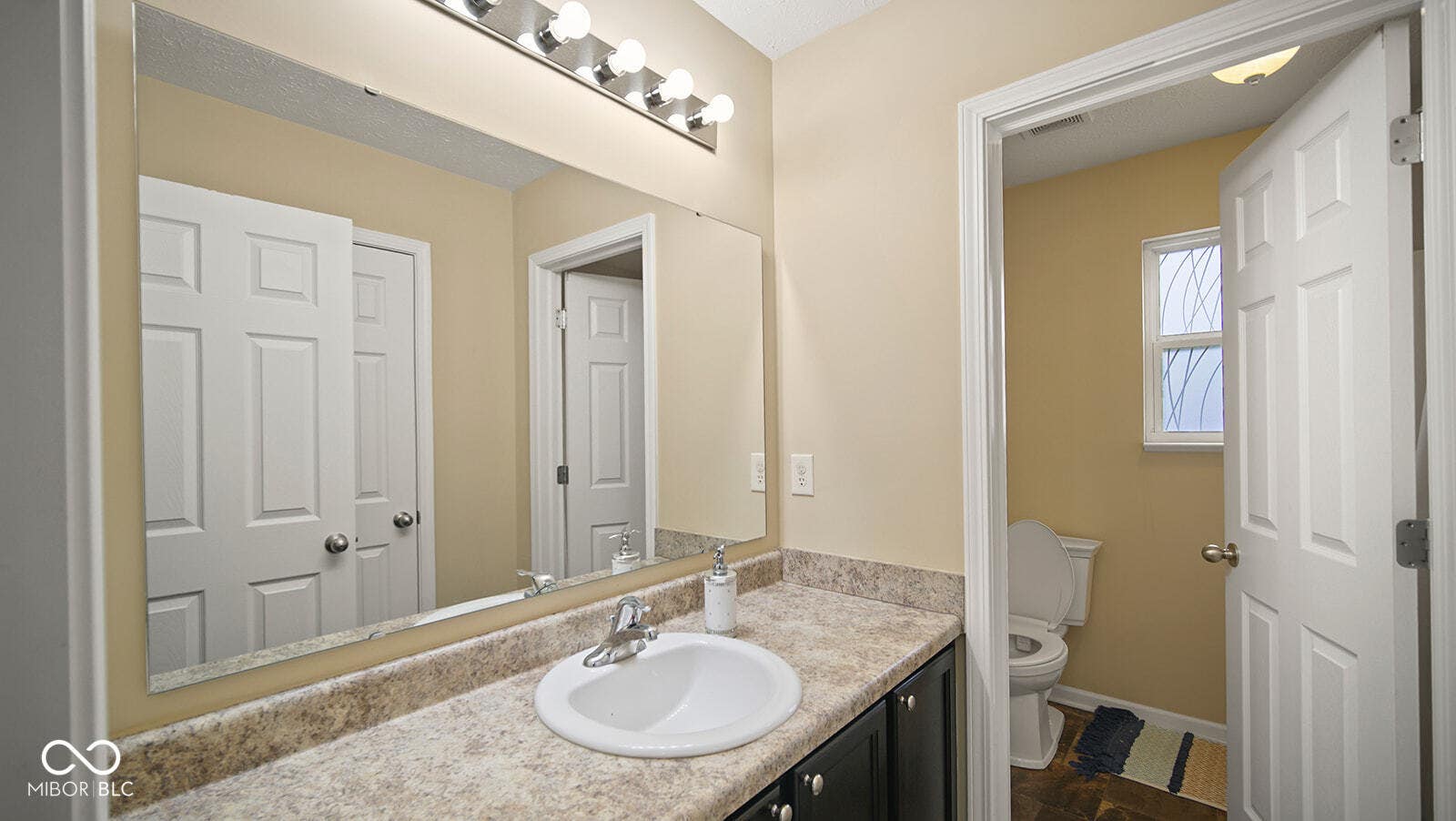 half bath featuring baseboards, visible vents, toilet, and vanity