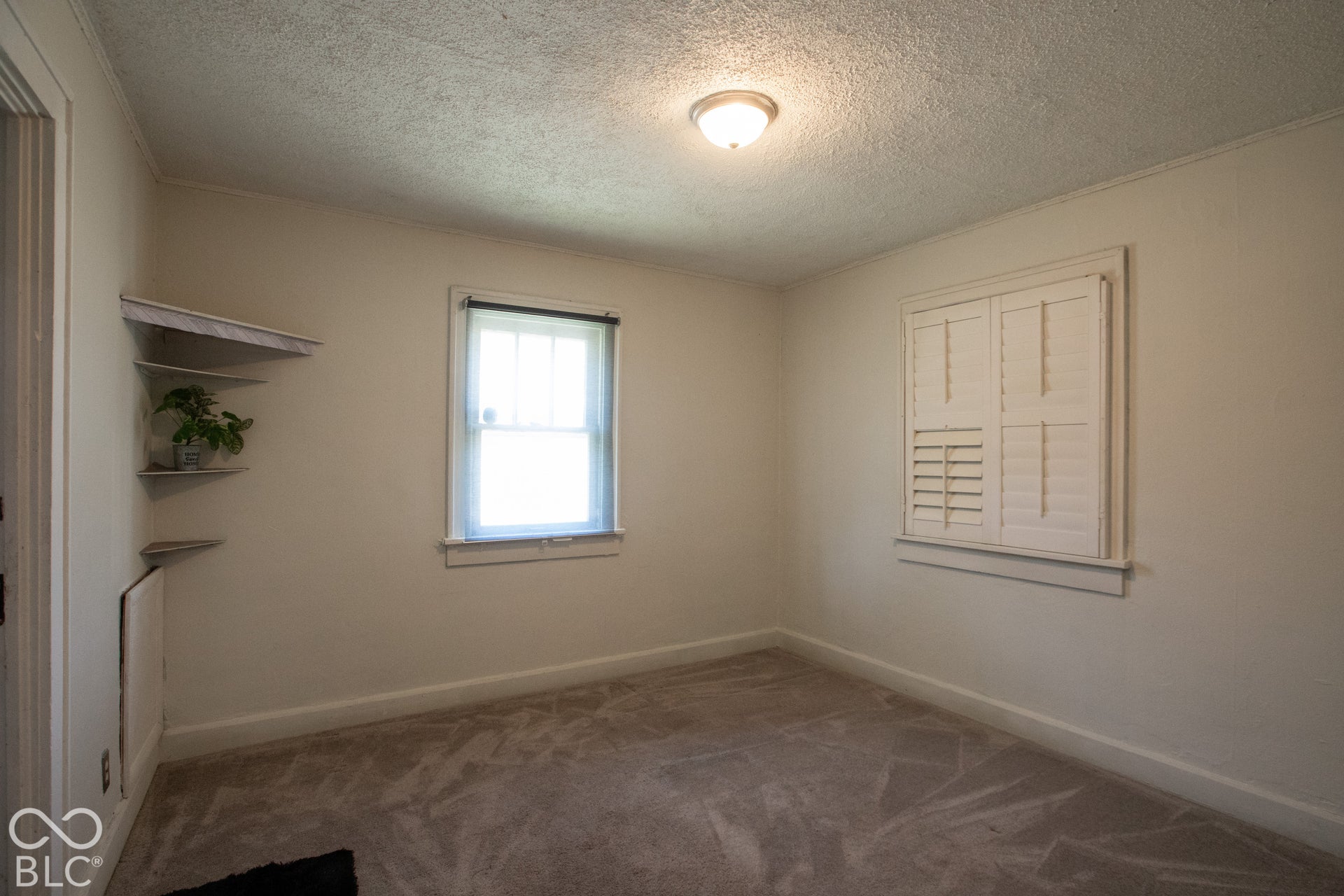 Recessed corner shelving, flush-mount ceiling light fixture, and window with plantation shutters