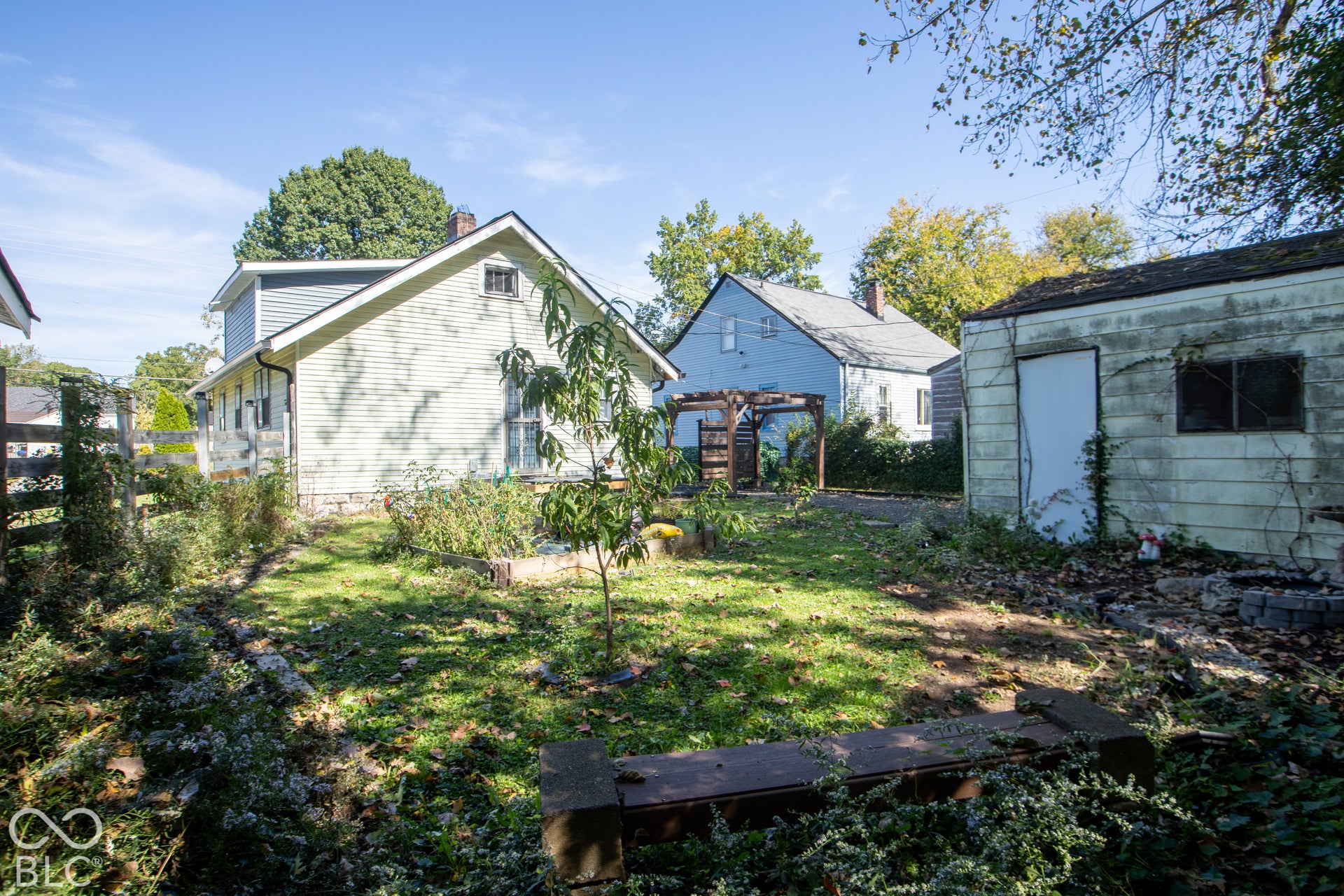 Rear exterior featuring a detached shed, partial wood fencing, and a small tree