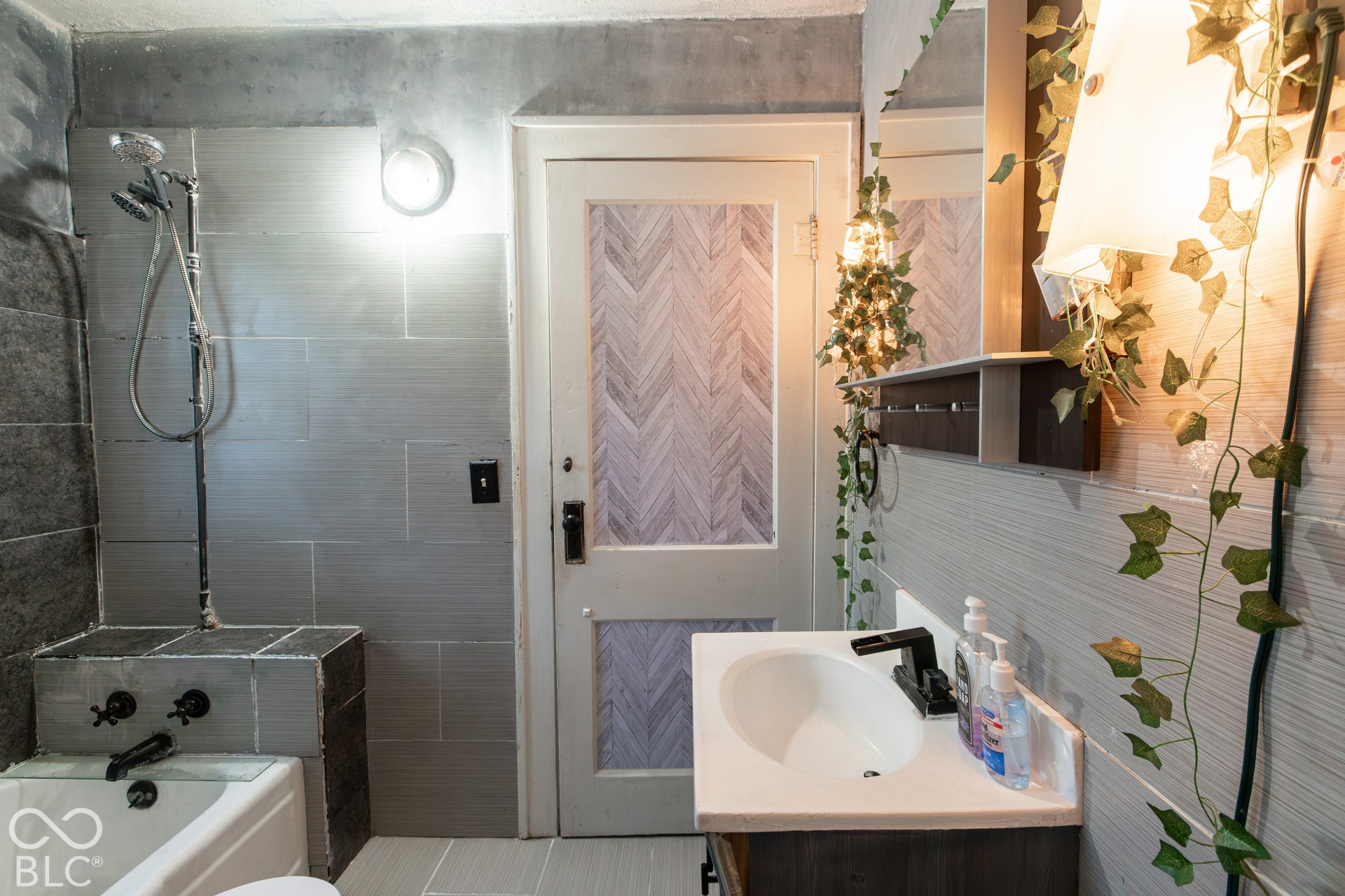 Bathroom featuring a white bathtub, tiled shower surround, and a vanity with a white sink