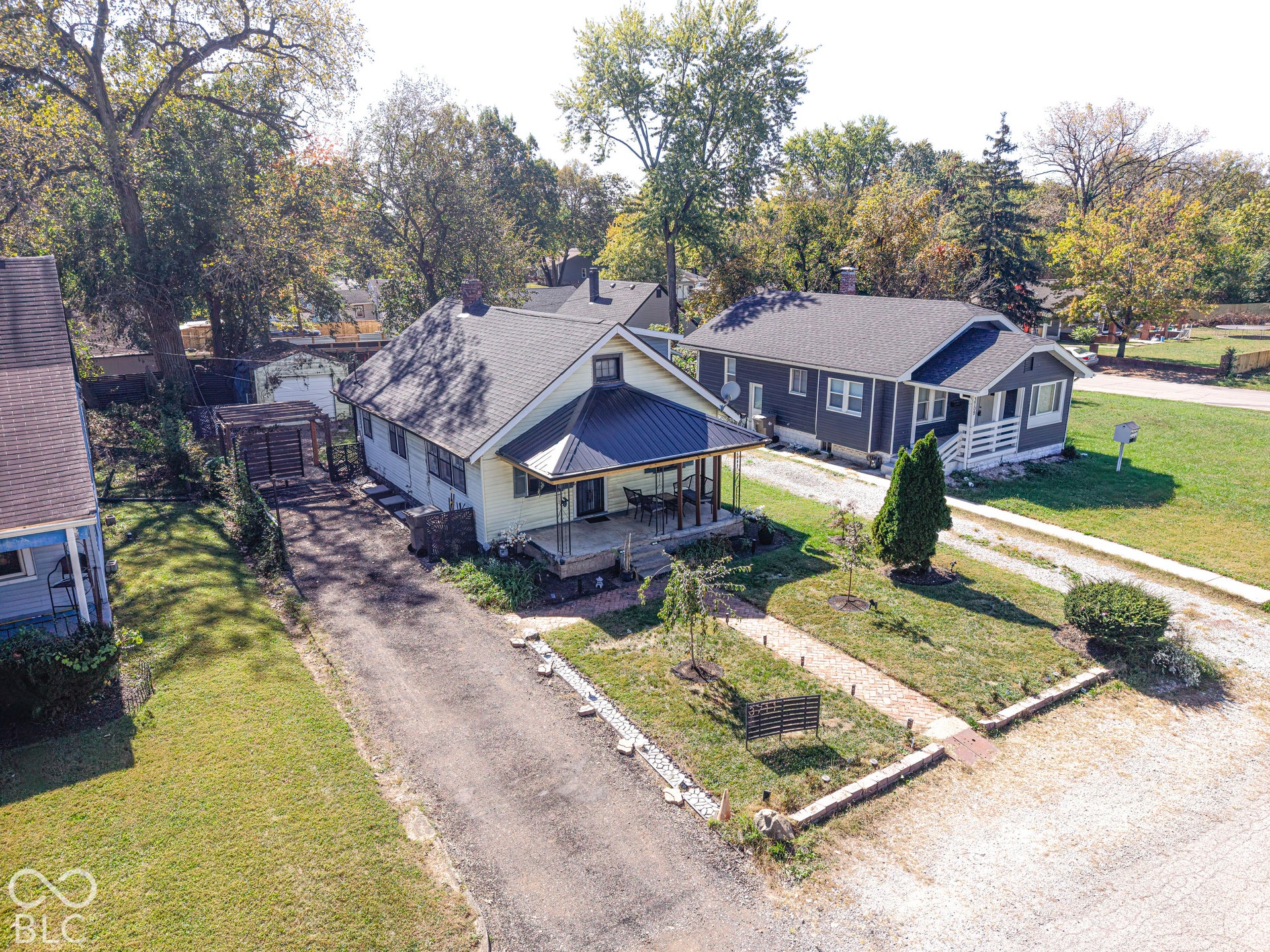 Gabled roofline with metal accent, covered front porch, asphalt driveway, and mature landscaping
