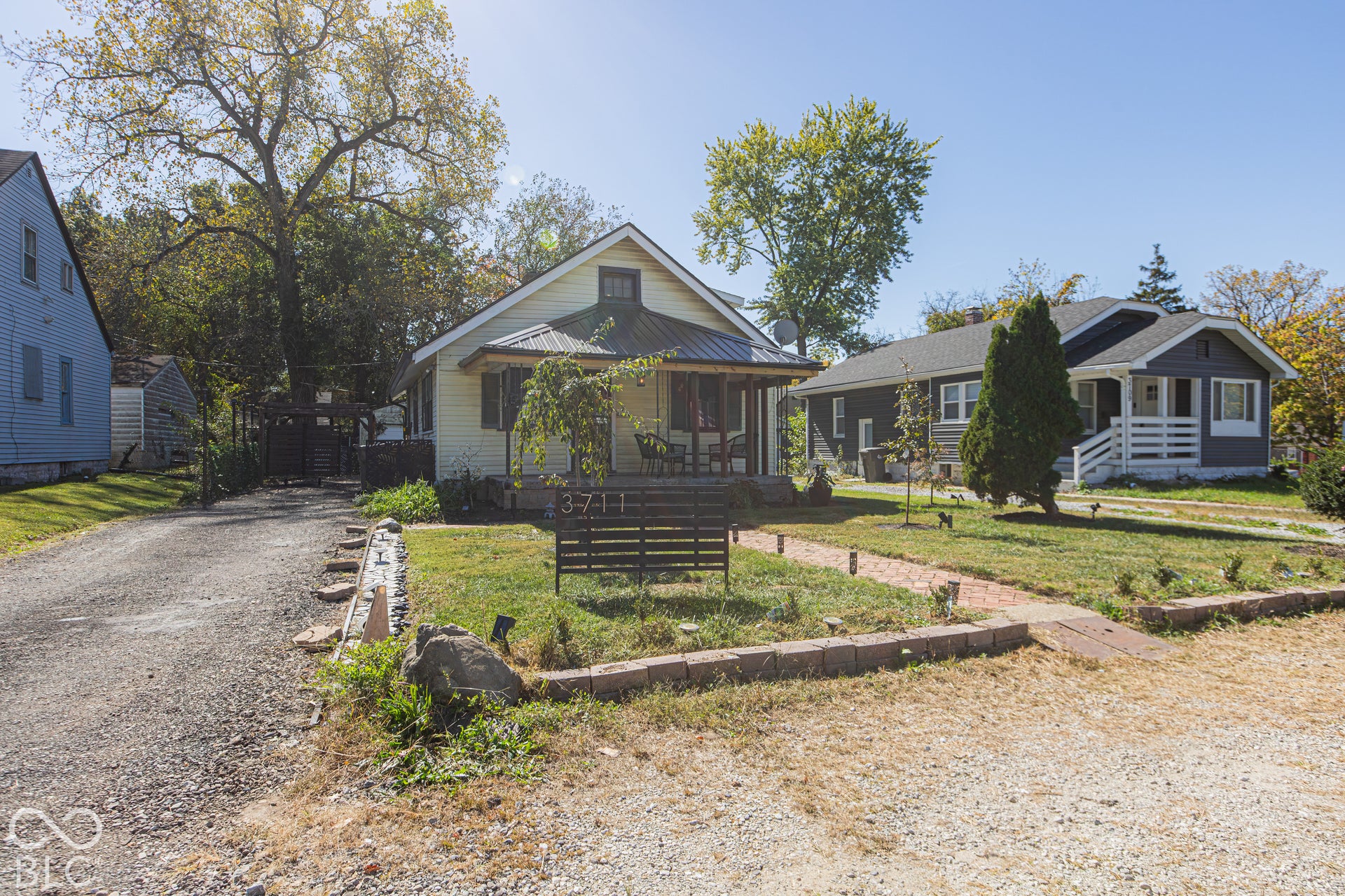 Charming exterior with a covered porch, gravel driveway, and a brick pathway