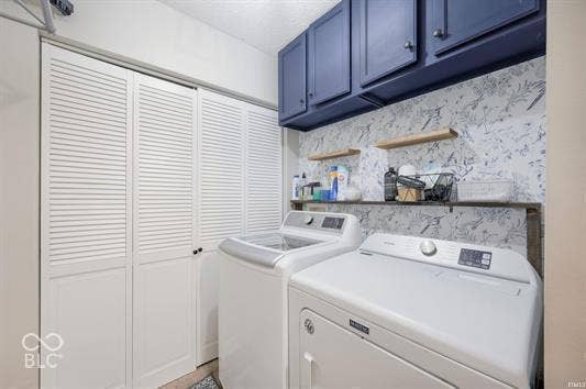 Integrated laundry area featuring louvered bi-fold doors, dark blue cabinetry, and open shelving