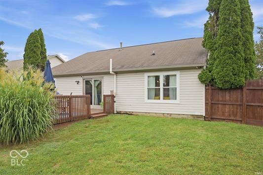 Exterior featuring light-colored siding, a brown roof, and a wooden privacy fence
