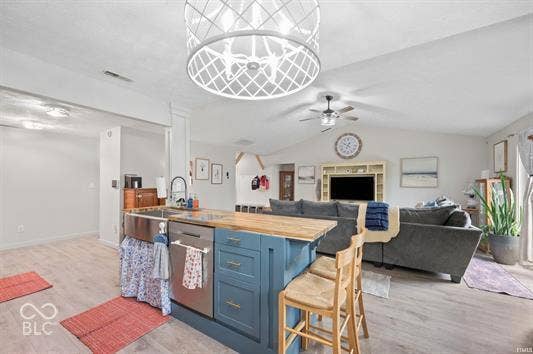 Kitchen island with wood-finish countertop, stainless steel farmhouse sink, and integrated dishwasher