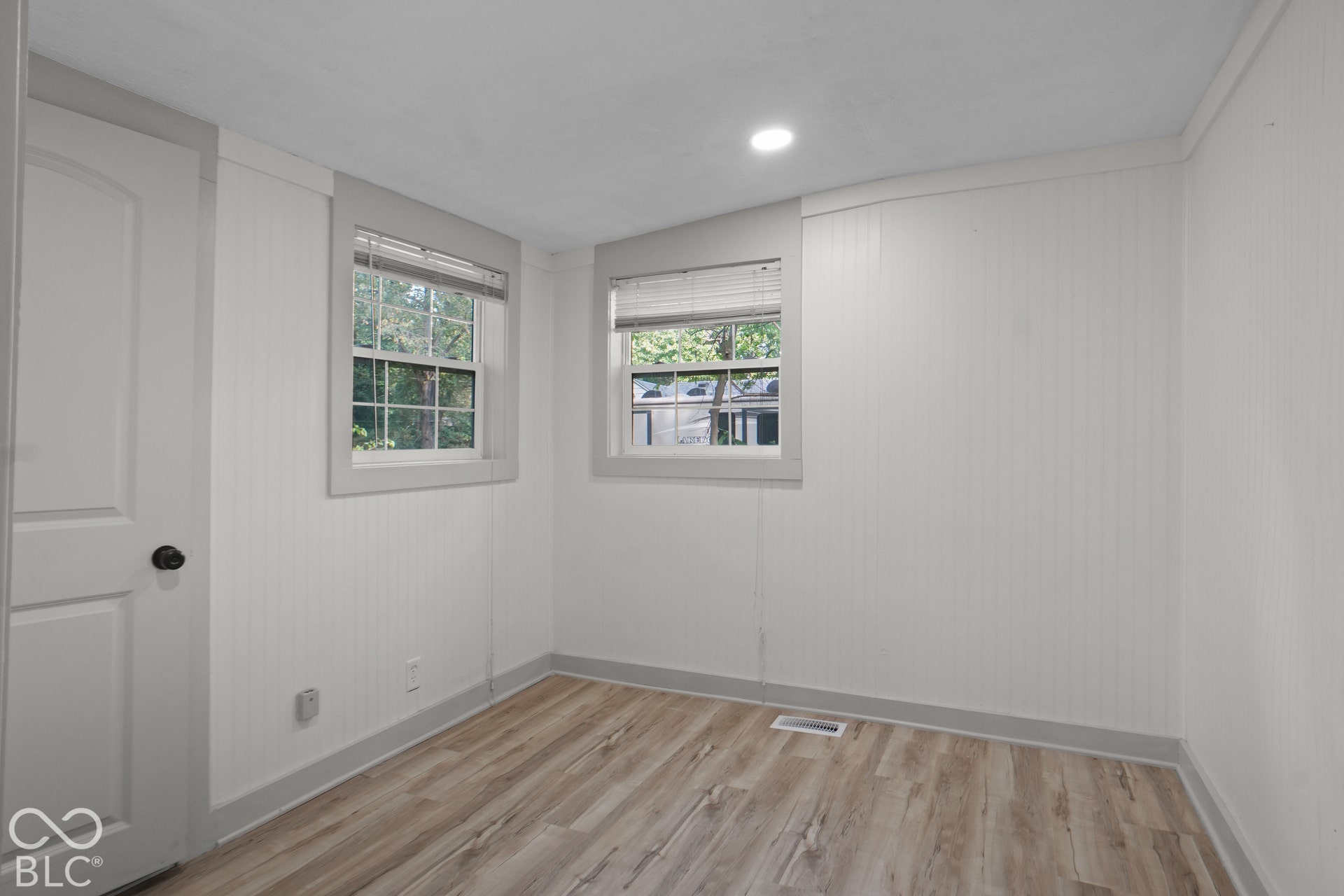 Wood-finish flooring, recessed ceiling light, and vertical wall paneling