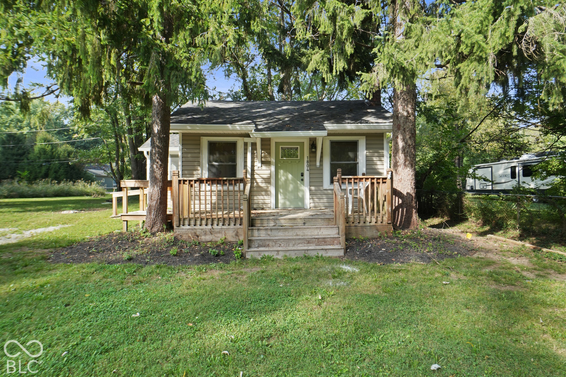 Wood-sided exterior featuring a light green entry door, a gabled roof, and a front porch with wood railings