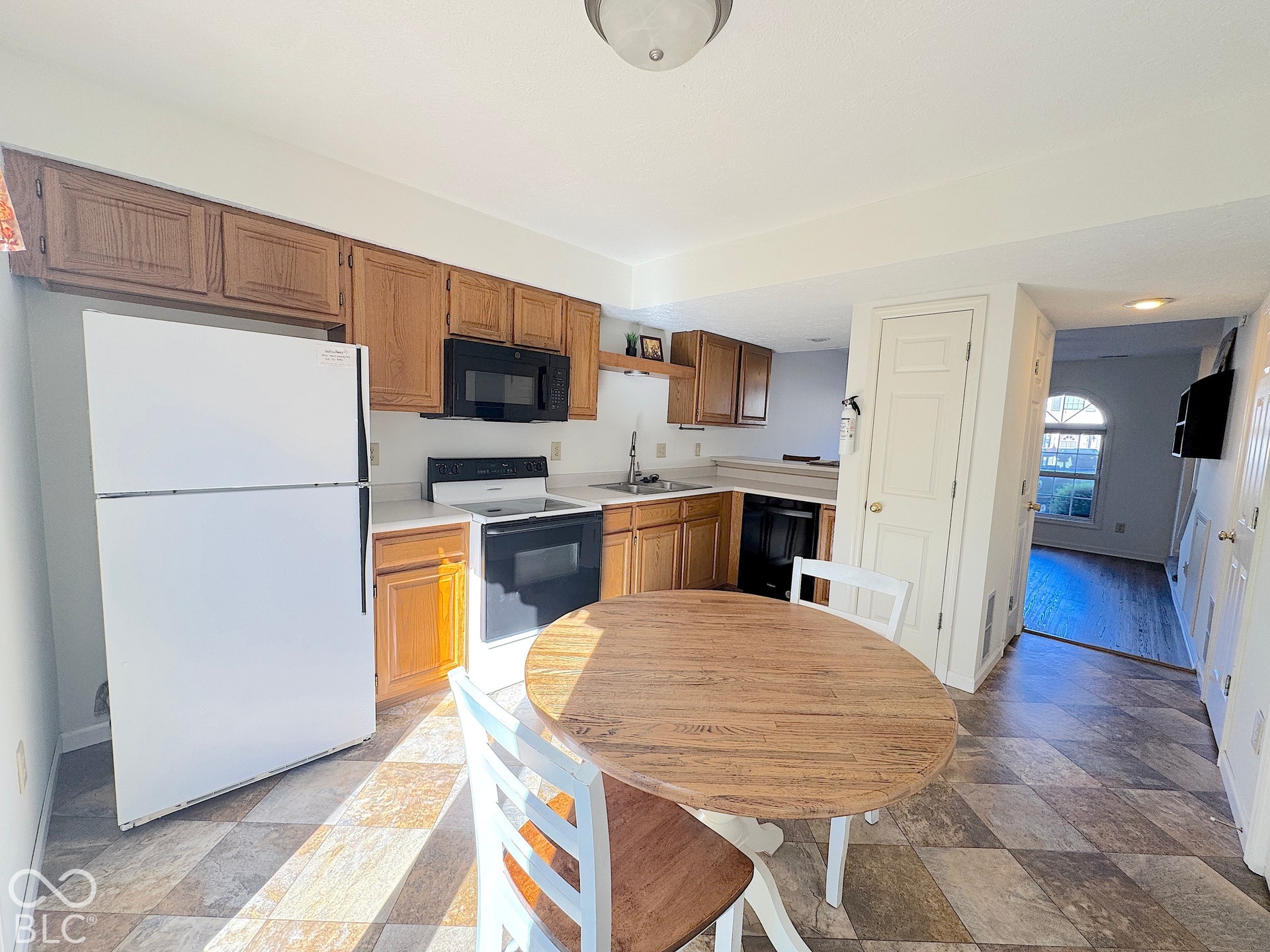 Kitchen featuring wood-finish cabinetry, black appliances, white appliances, and patterned flooring