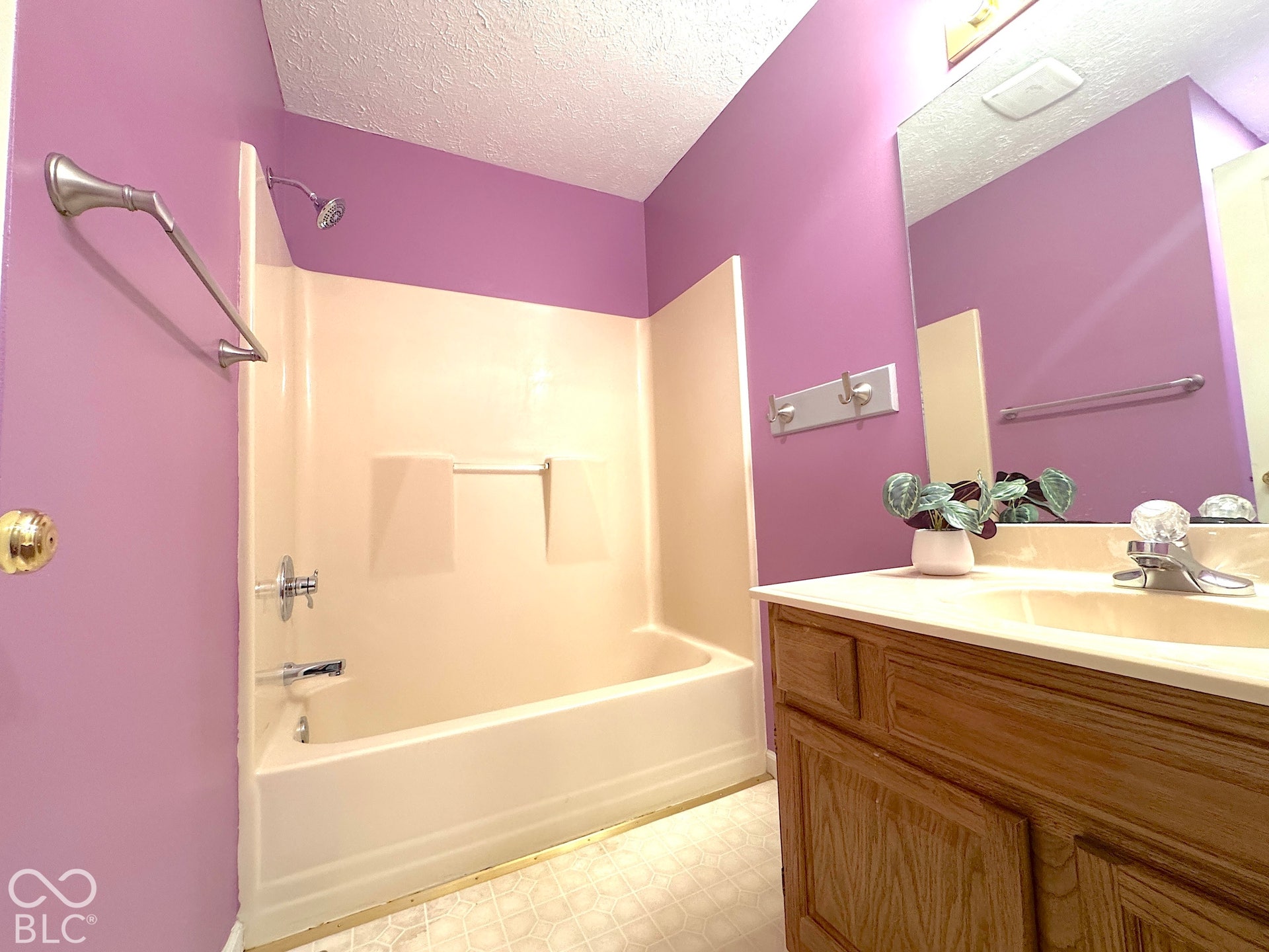 Bathroom featuring a built-in bathtub with shower, a vanity with an integrated sink, an overhead mirror, and wood-finish cabinetry