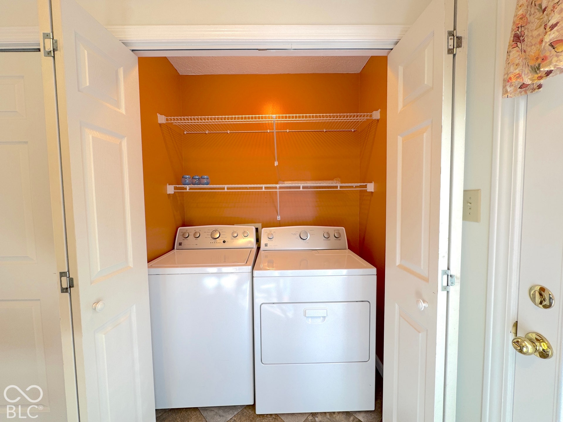 Dedicated laundry area with upper shelving and bifold doors