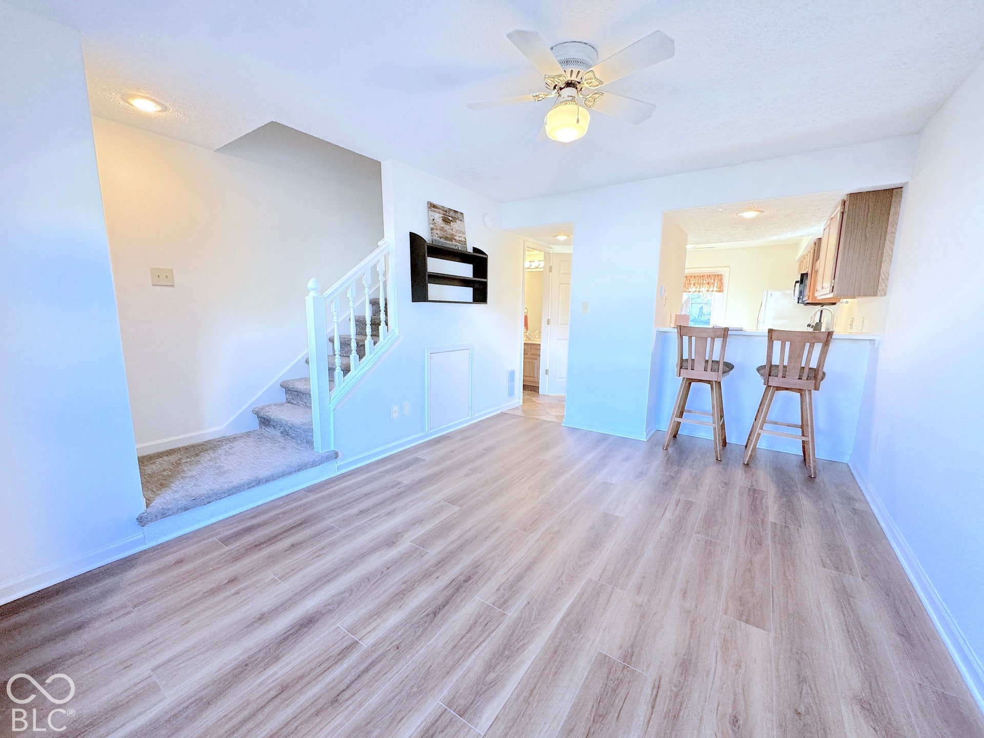 Wood-finish flooring, white walls, and a ceiling fan with integrated lighting