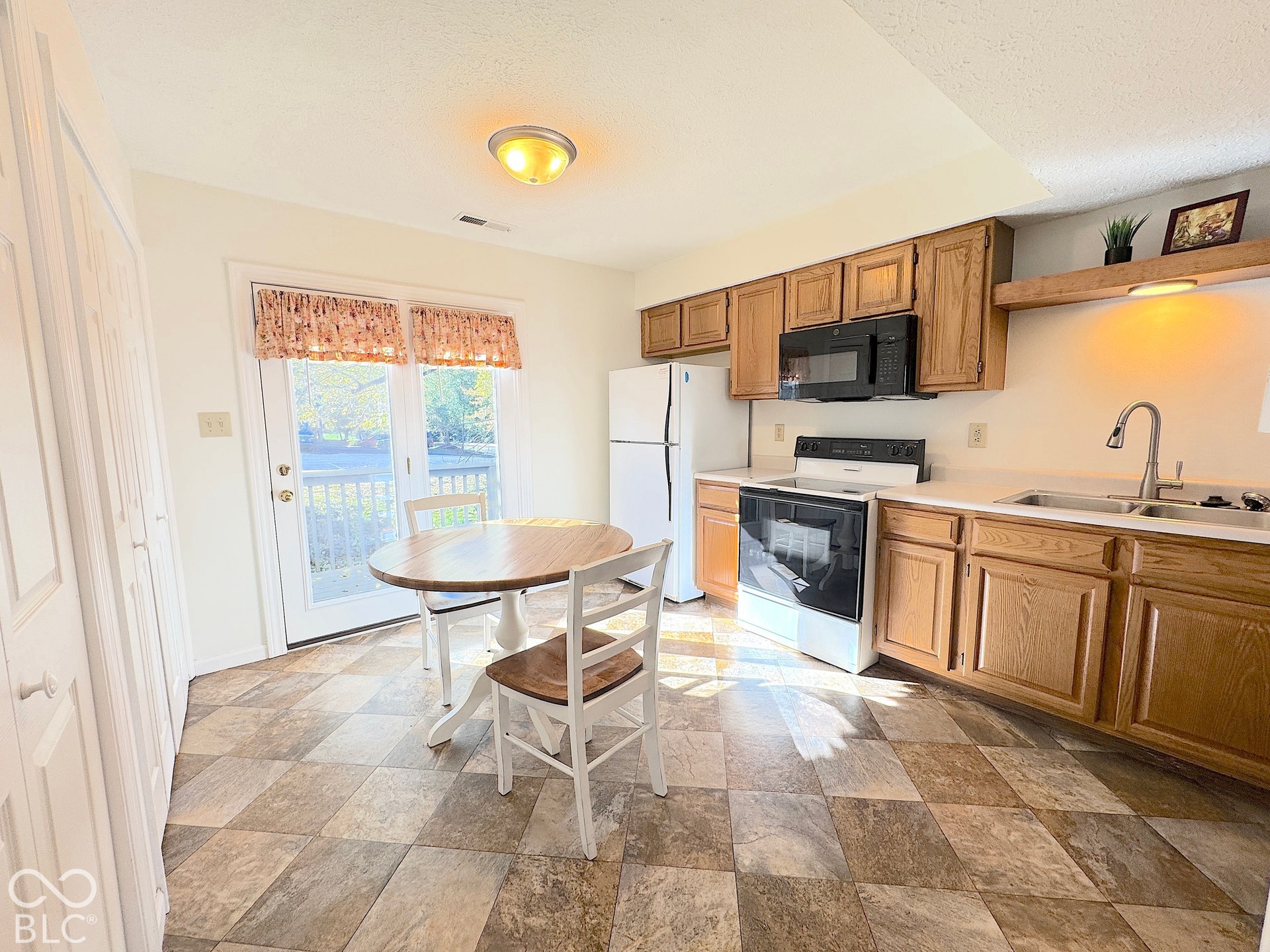 Kitchen featuring wood-finish cabinetry, a stainless steel sink, and white appliances