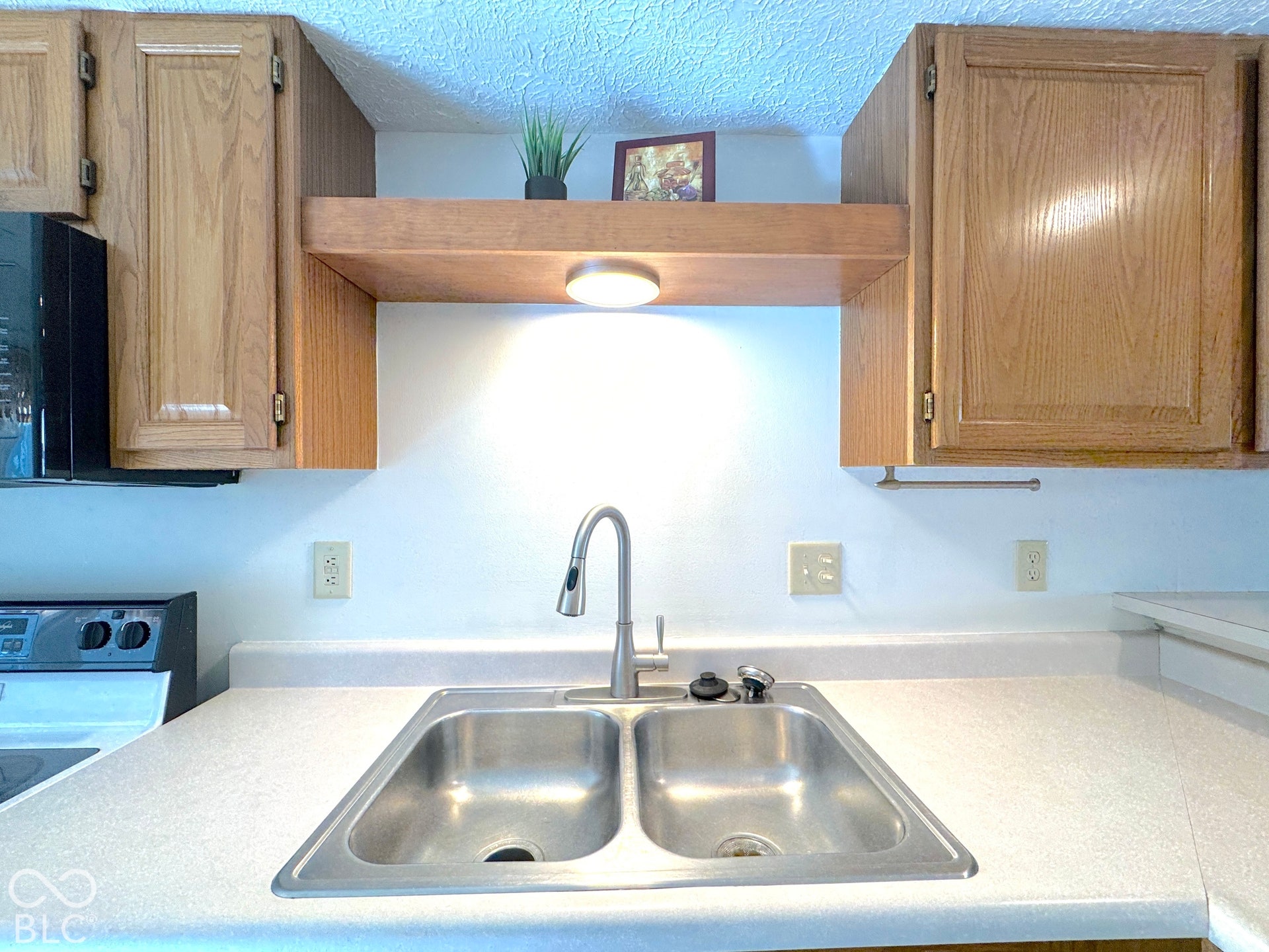 Dual basin stainless steel sink with a high-arc faucet, set within light-toned countertops
