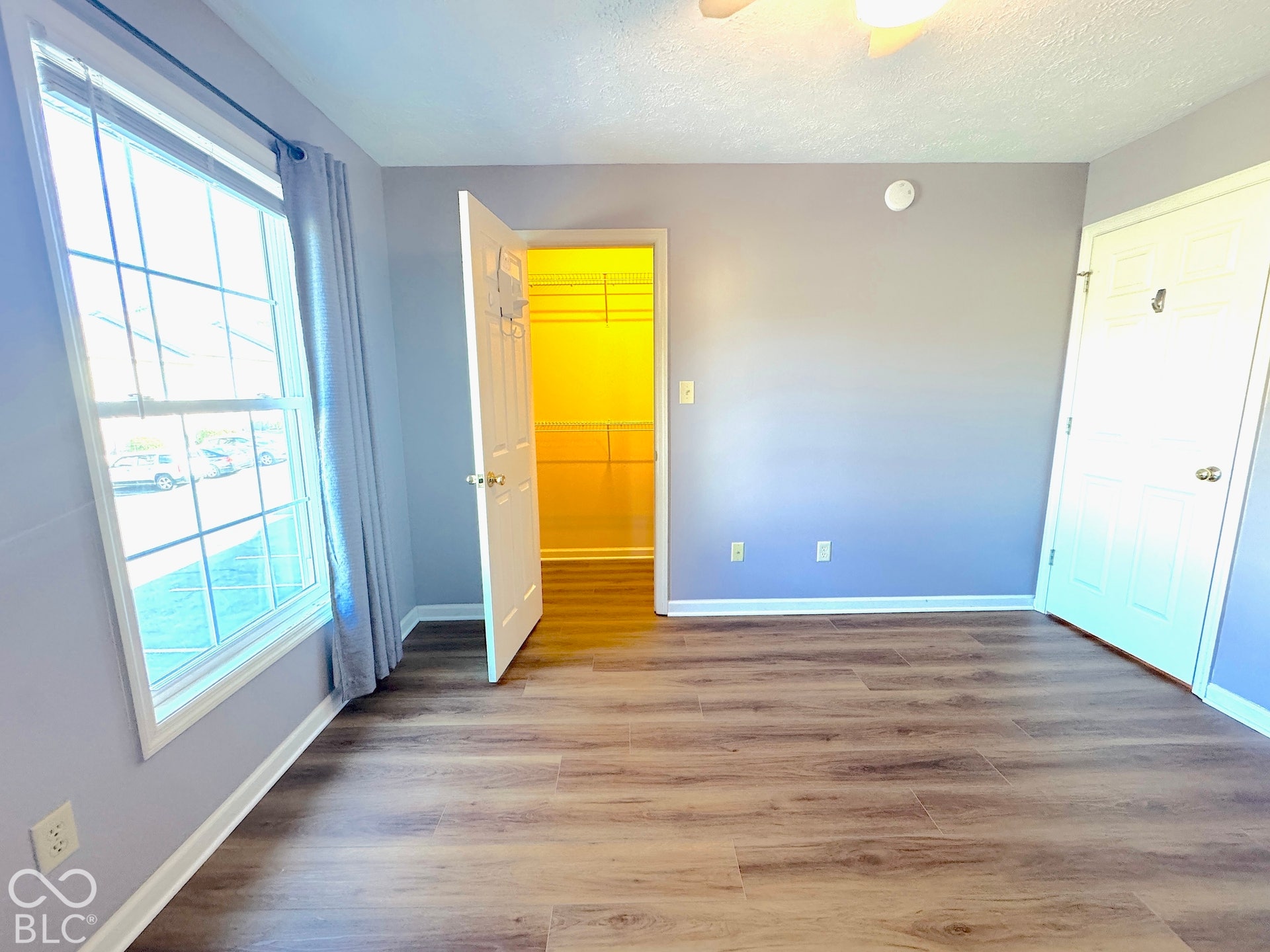 Wood-finish flooring, ceiling fan, and a large window
