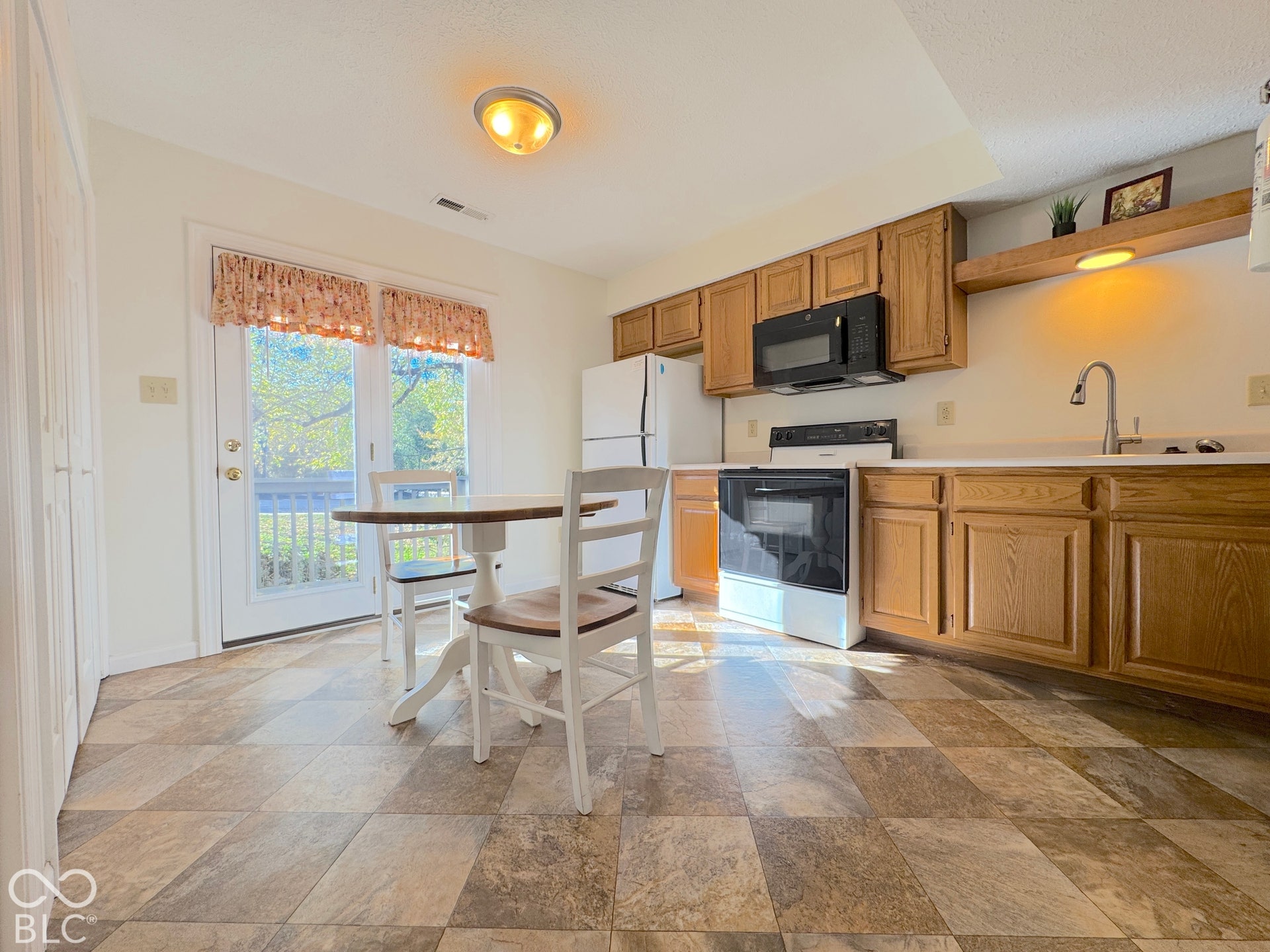Kitchen featuring wood-finish cabinetry, white countertops, built-in microwave, and a stainless steel sink with a gooseneck faucet