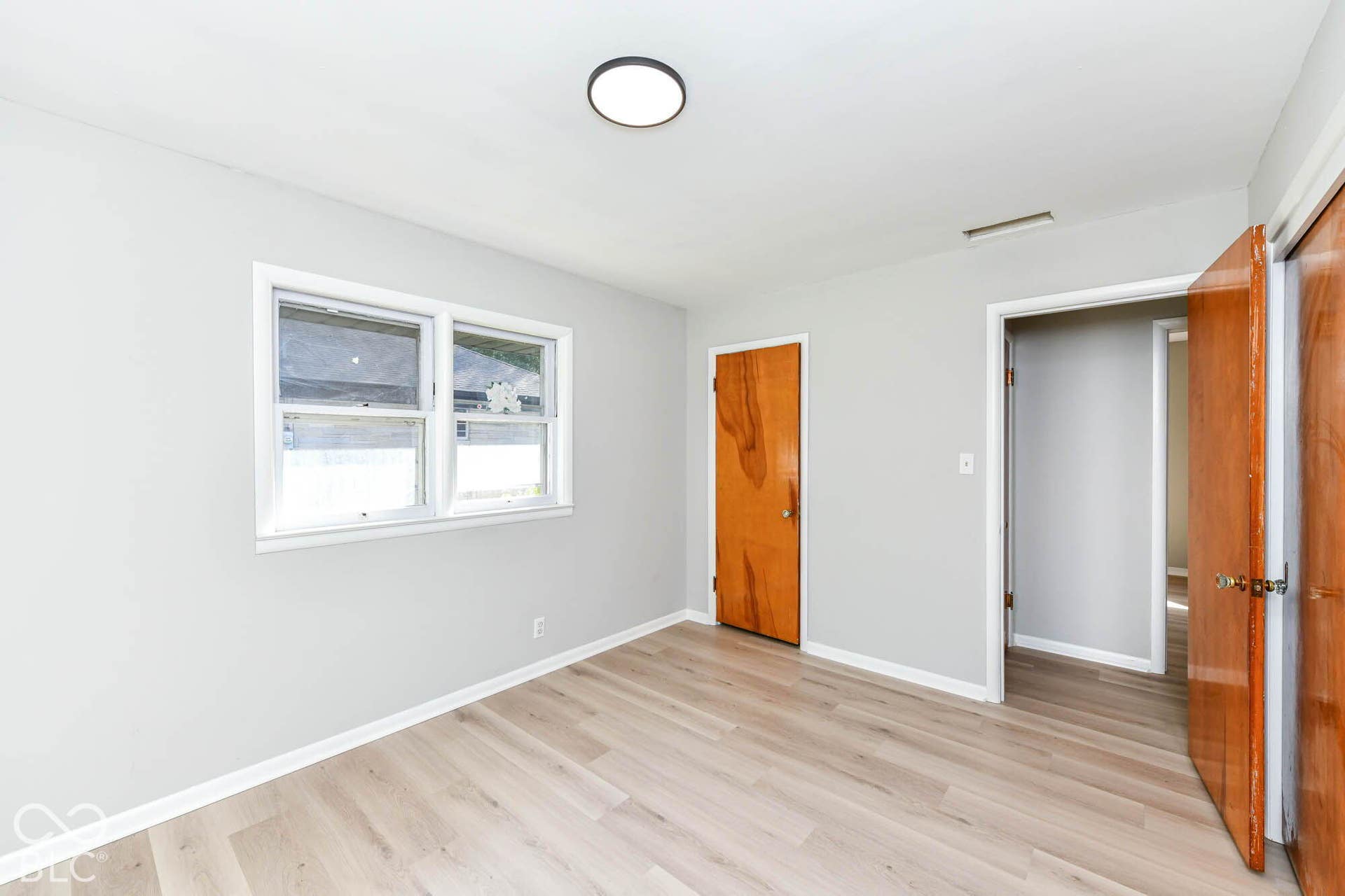 6401 Orinoco Avenue, Indianapolis, IN 46227 Light wood-finish flooring with white baseboards, a double window with white trim, and a flush mount ceiling light