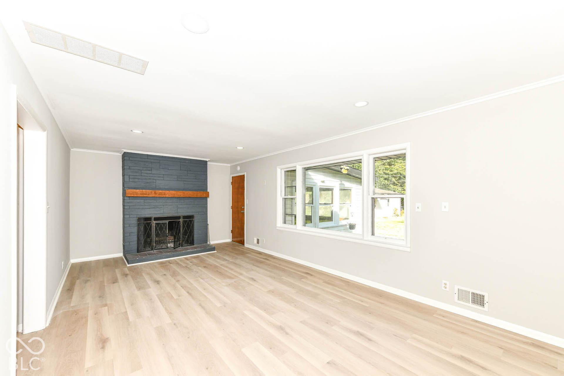 6401 Orinoco Avenue, Indianapolis, IN 46227 Spacious room featuring a painted brick fireplace with a wood mantel, wood-finish flooring, recessed lighting, and multiple windows