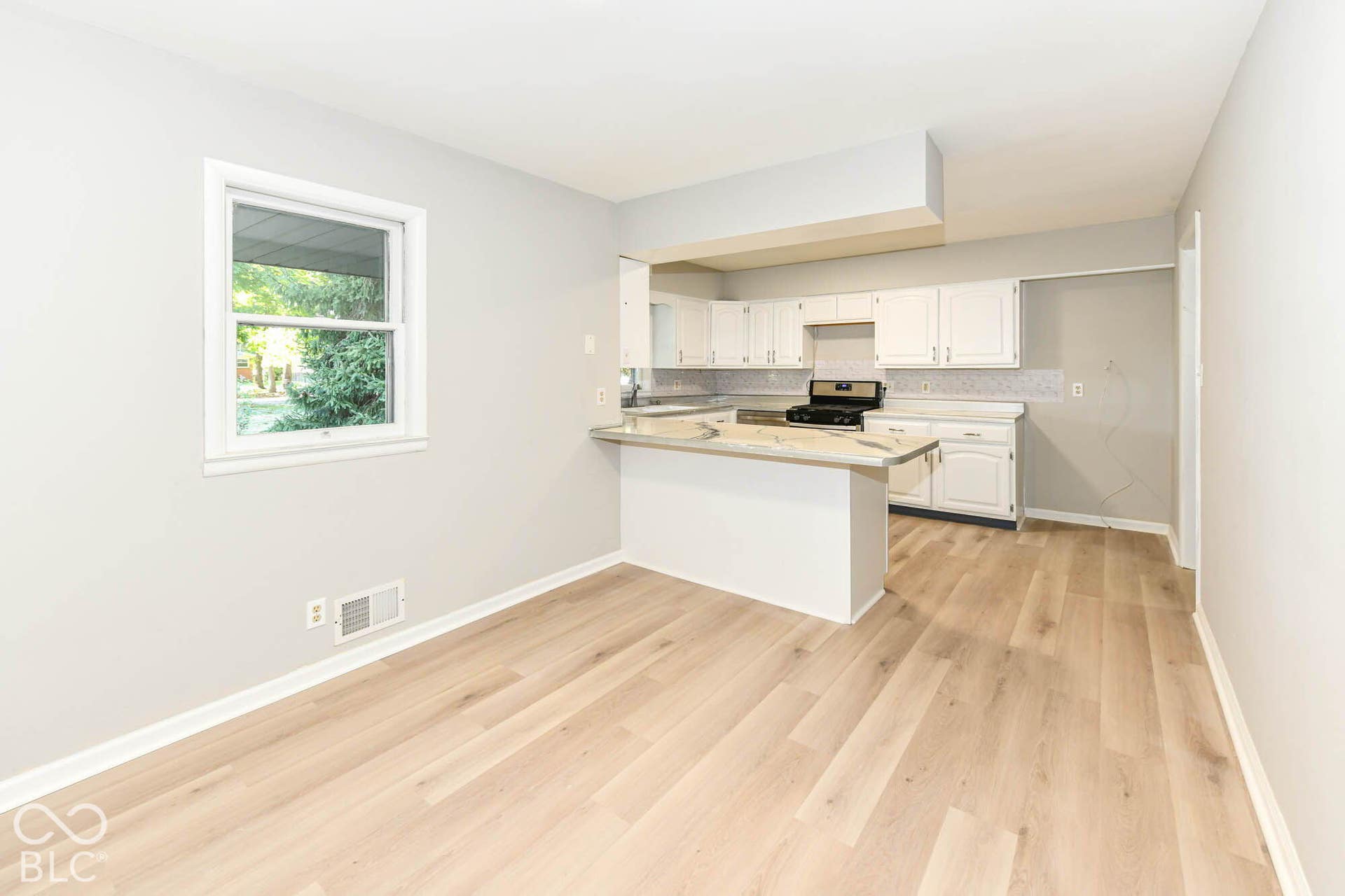 6401 Orinoco Avenue, Indianapolis, IN 46227 Well-appointed kitchen featuring white cabinetry, light-toned countertops, a tile backsplash, a black range, and a breakfast bar