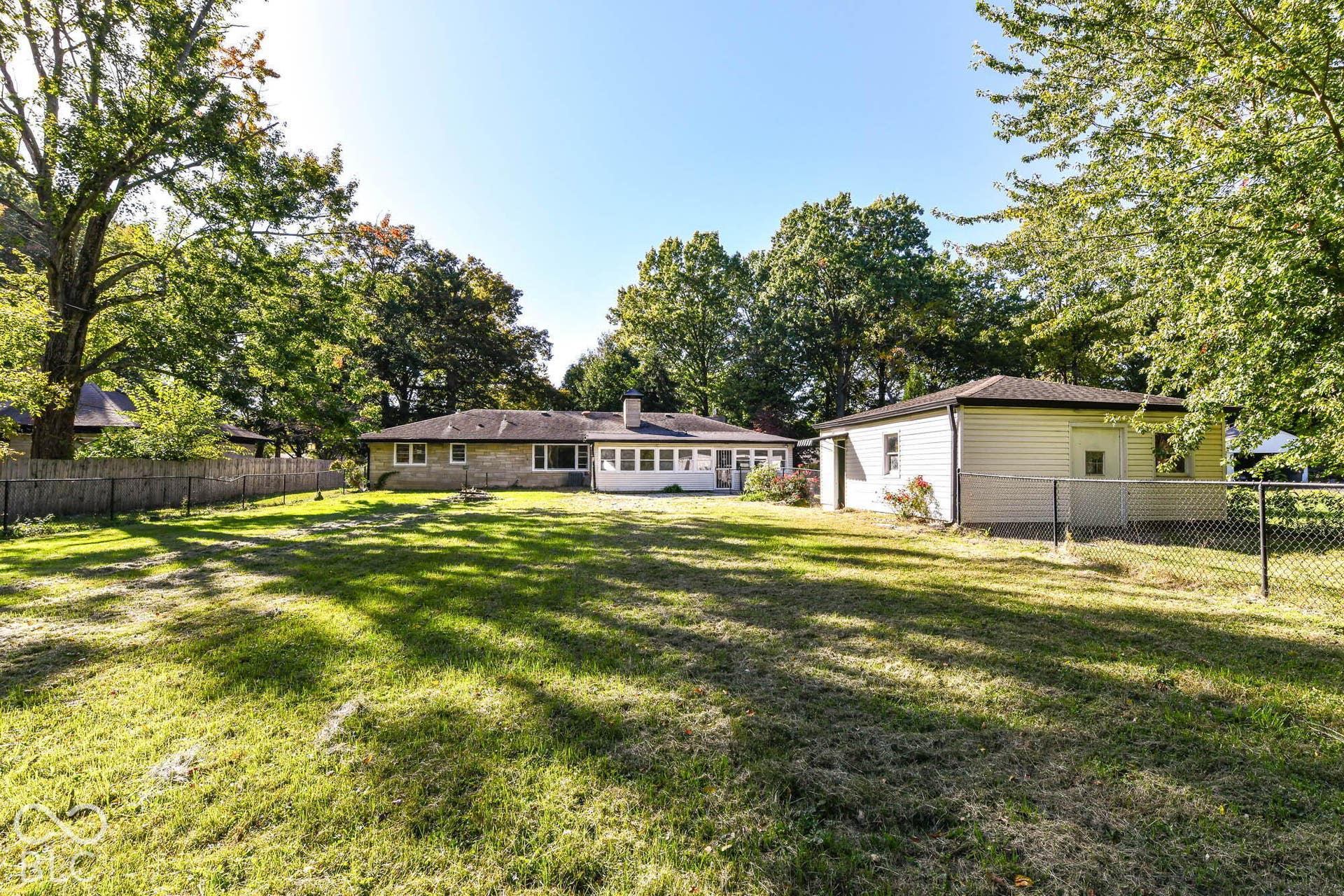6401 Orinoco Avenue, Indianapolis, IN 46227 Expansive property featuring a stone exterior residence, a separate detached building, and a chain-link fence