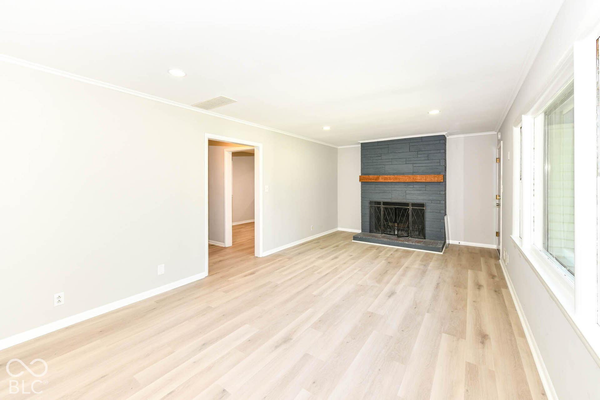 6401 Orinoco Avenue, Indianapolis, IN 46227 Spacious living area featuring wood-finish flooring, a stone fireplace with a wood mantle, and bright window installations