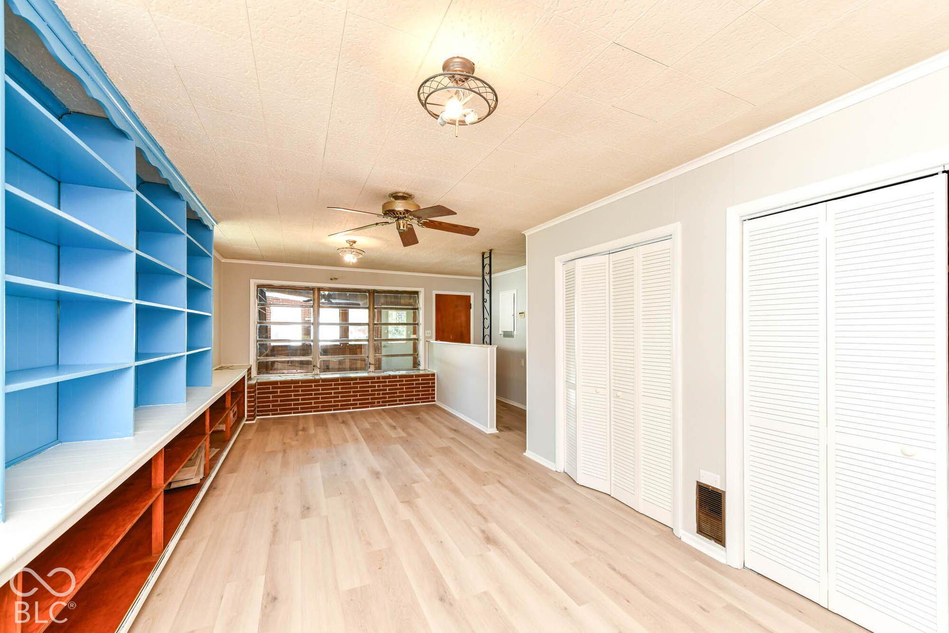 6401 Orinoco Avenue, Indianapolis, IN 46227 Built-in shelving, wood-finish flooring, white louvered bifold doors, window with brick-finish sill, and ceiling fan