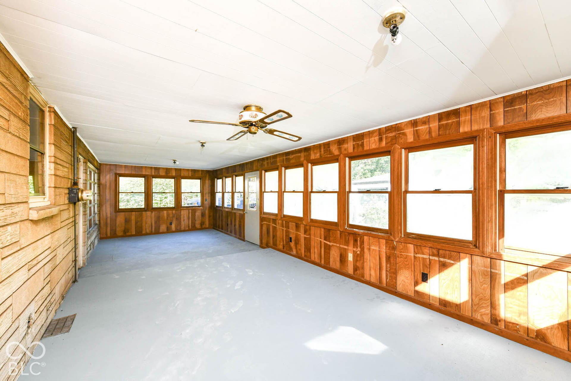 6401 Orinoco Avenue, Indianapolis, IN 46227 Enclosed patio featuring extensive window banks, wood-paneled walls, a ceiling fan, and painted flooring