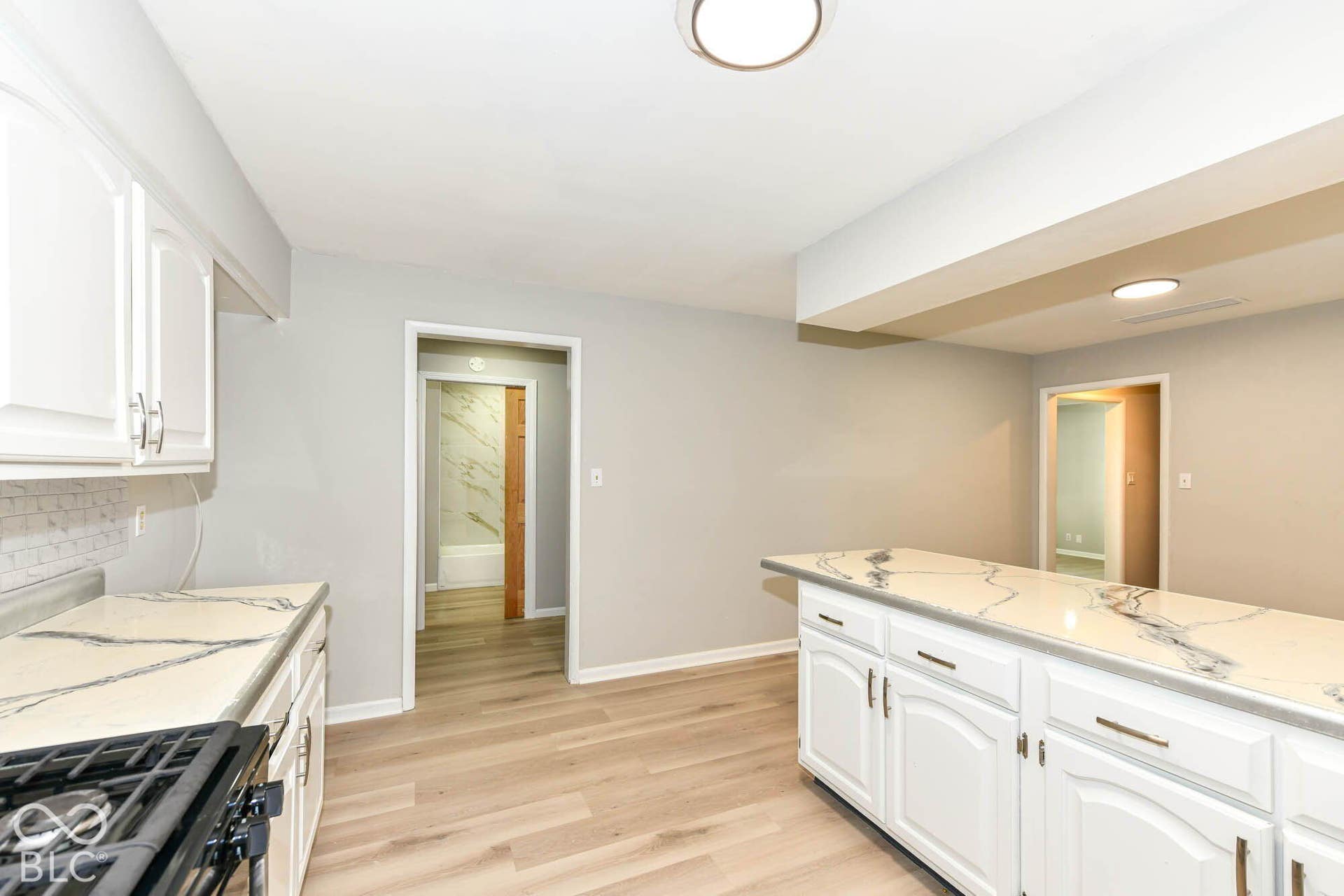 6401 Orinoco Avenue, Indianapolis, IN 46227 Kitchen featuring white cabinetry, quartz-style countertops, mosaic tile backsplash, and light wood-finish flooring