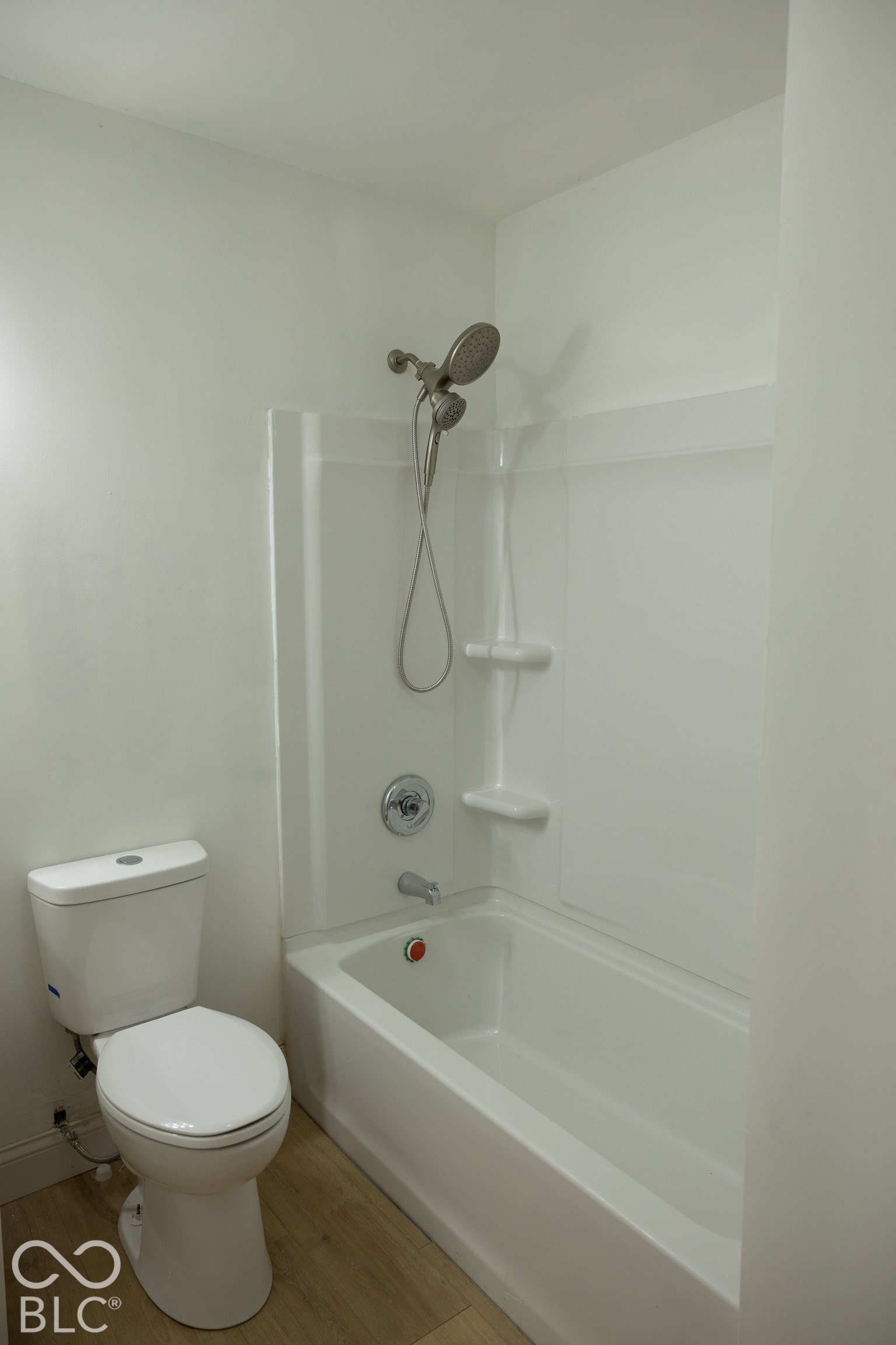 White bathtub with integrated shower, chrome fixtures, and a dual-function shower head