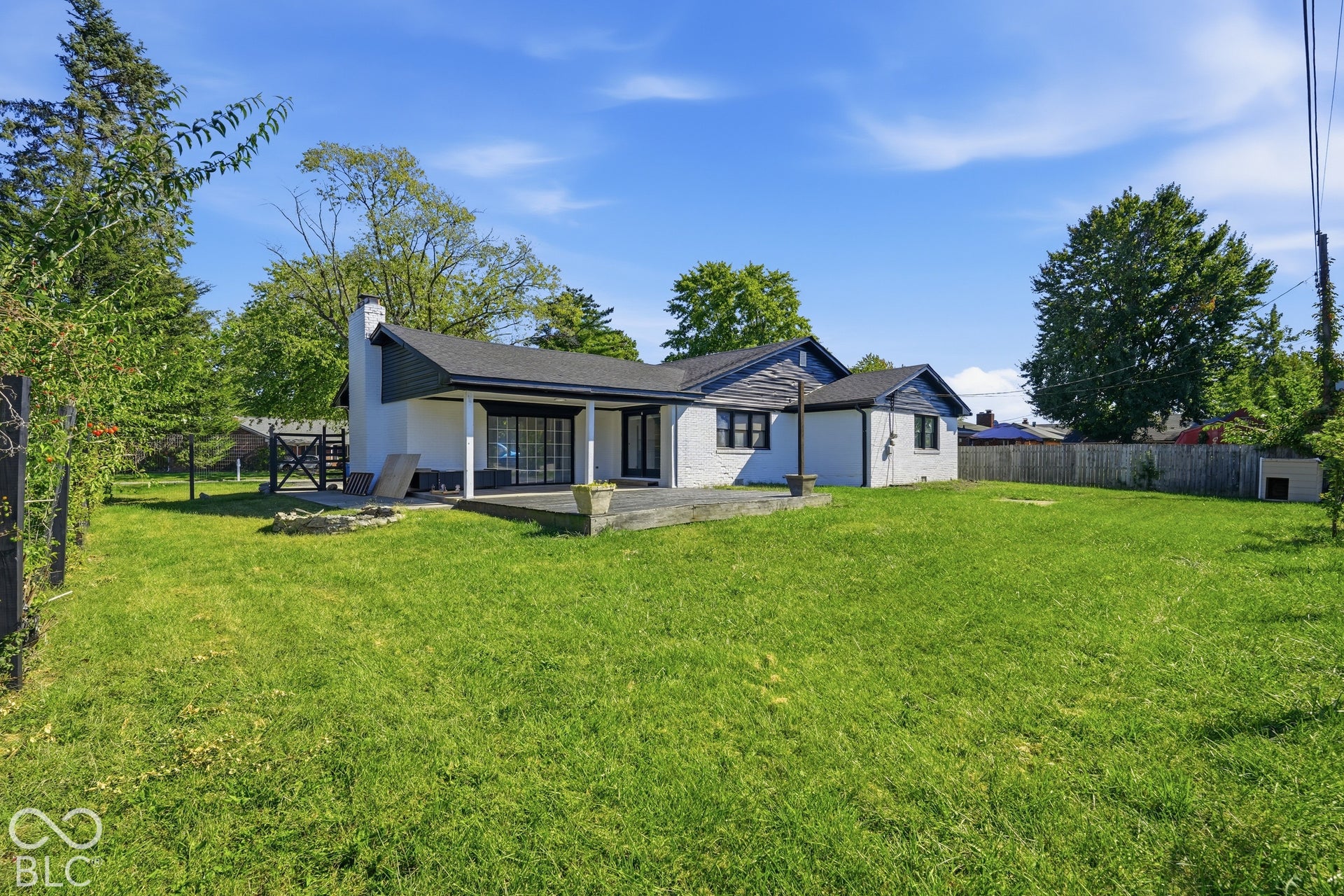 Expansive rear yard with a fire pit area and mature perimeter trees