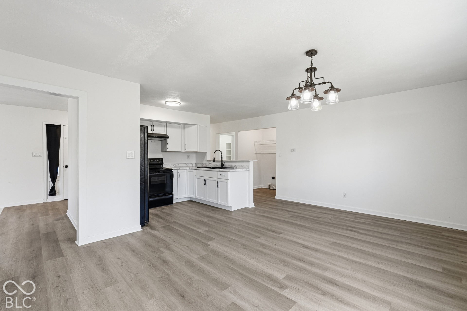 Kitchen with white cabinetry, black appliances, and a stainless steel sink with a black faucet