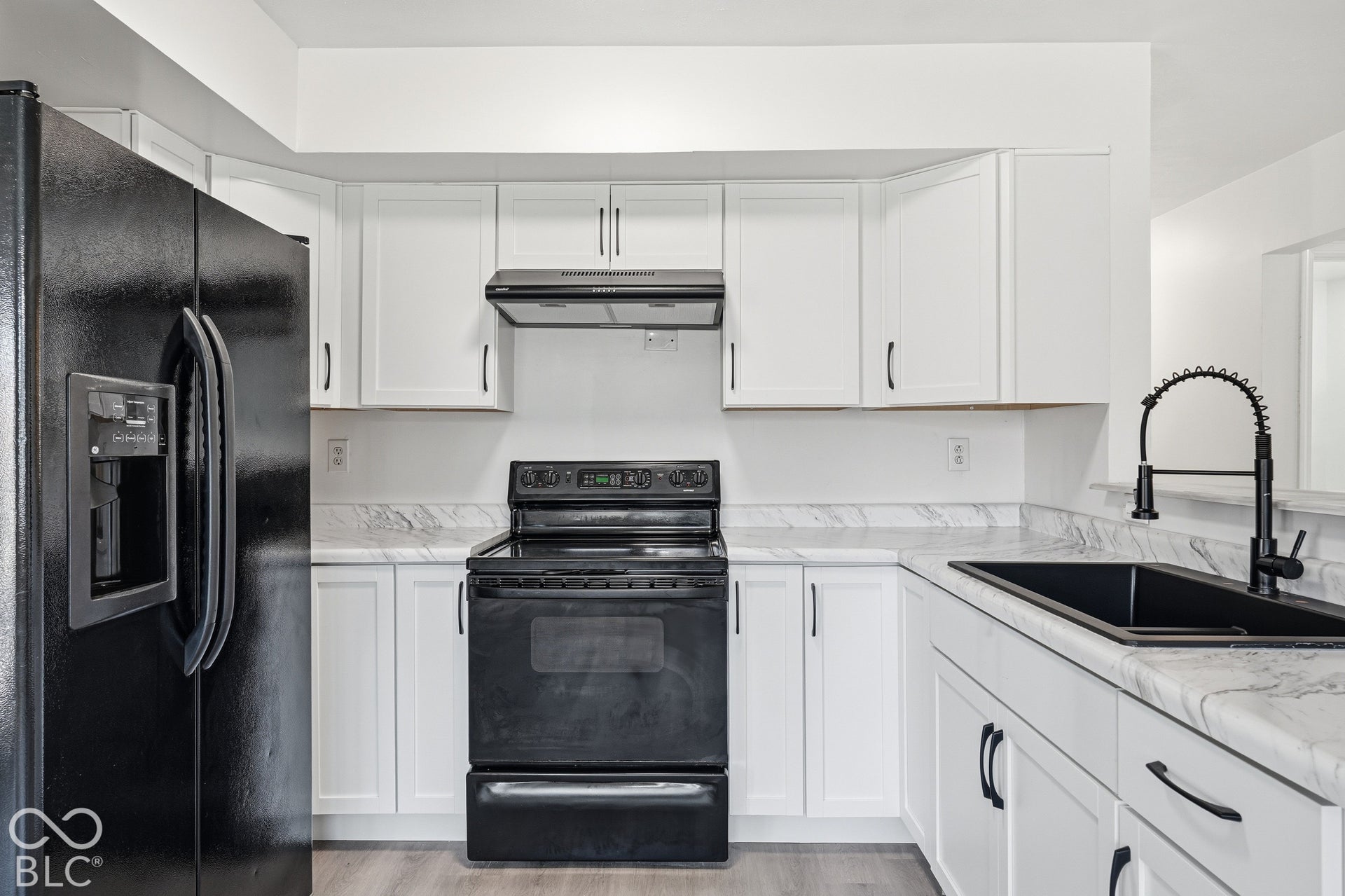 White cabinetry with black hardware, complementing black appliances, and a black sink with a flexible neck faucet