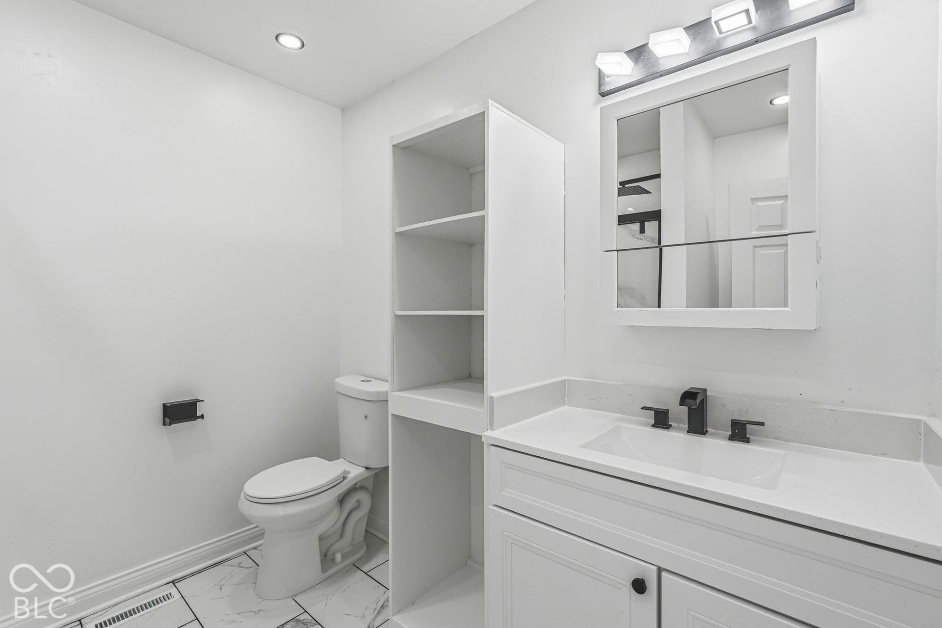 White vanity with integrated sink, black matte faucet, and white countertop