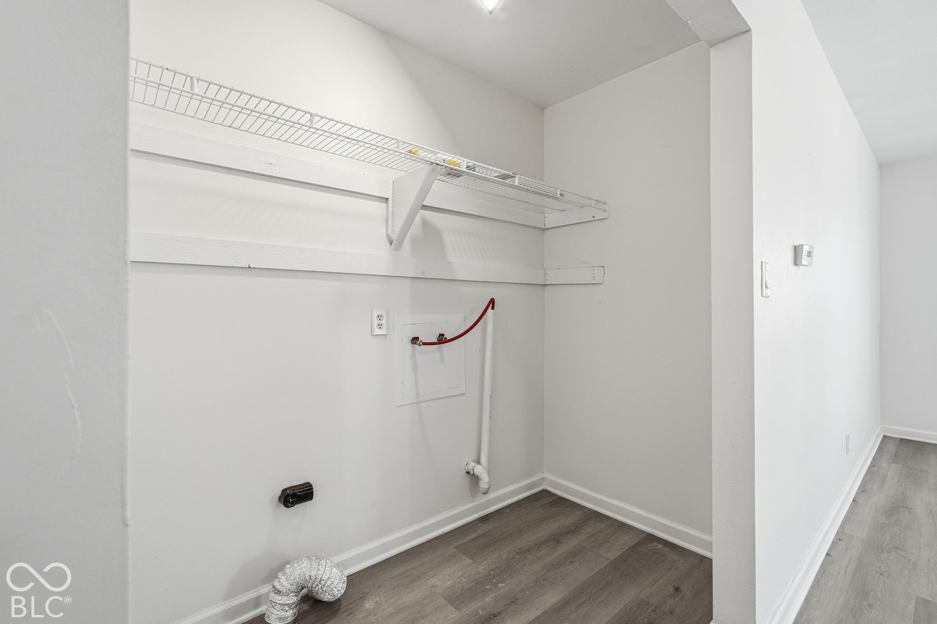 Dedicated utility area with wire shelving, wood-finish flooring, and crisp white walls