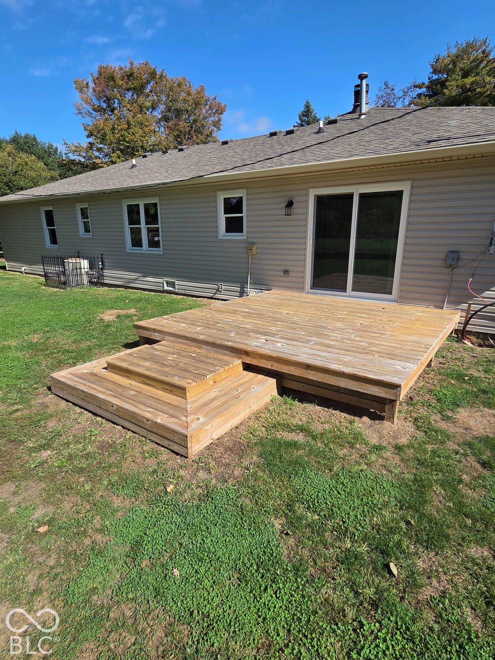 6614 Weil Drive, Brownsburg, IN 46112 Rear exterior with tan-colored siding, a wood-finish deck with steps, and a sliding glass door.