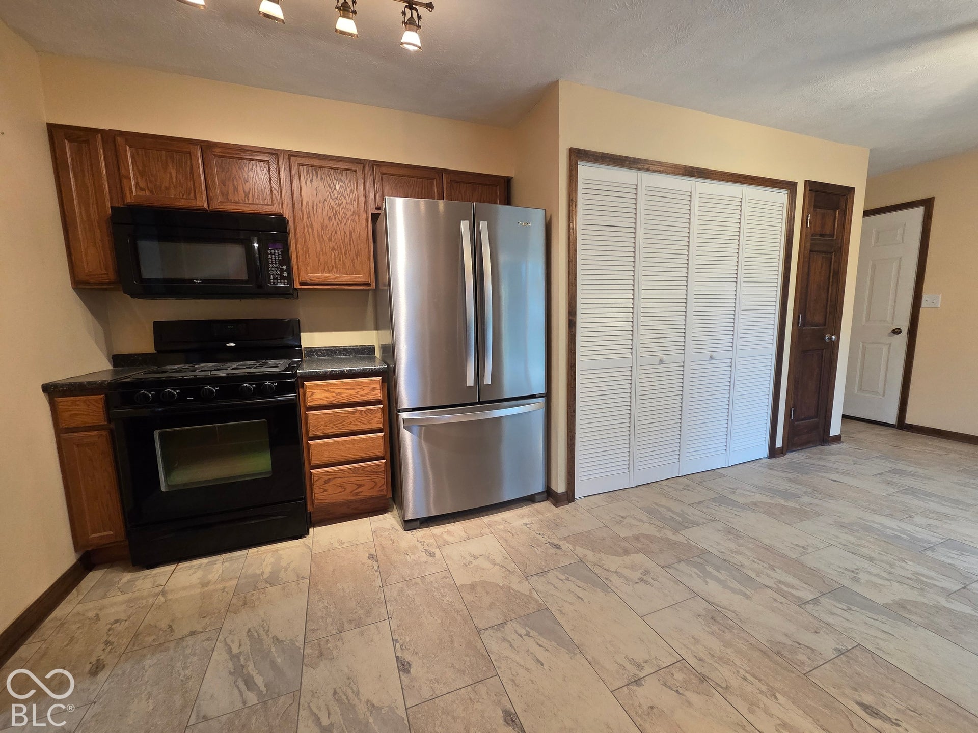 6614 Weil Drive, Brownsburg, IN 46112 Kitchen featuring wood cabinetry, stainless steel refrigerator, black range, black microwave, and tiled flooring