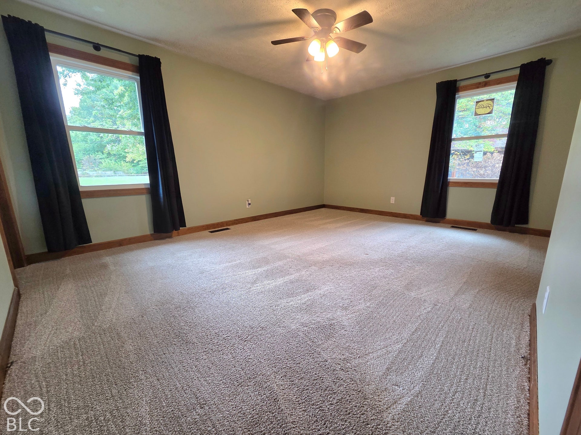 6614 Weil Drive, Brownsburg, IN 46112 Spacious room with plush carpeting, neutral wall finishes, a ceiling fan with integrated lighting, and two windows with wood-trim framing