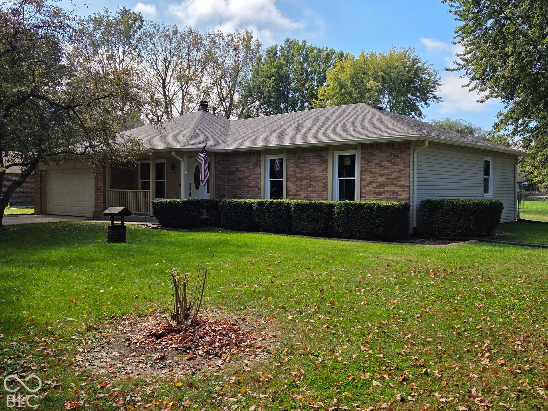 6614 Weil Drive, Brownsburg, IN 46112 Brick and siding exterior featuring a covered porch with railings, an attached 2 car garage, and a well-maintained lawn with mature trees.