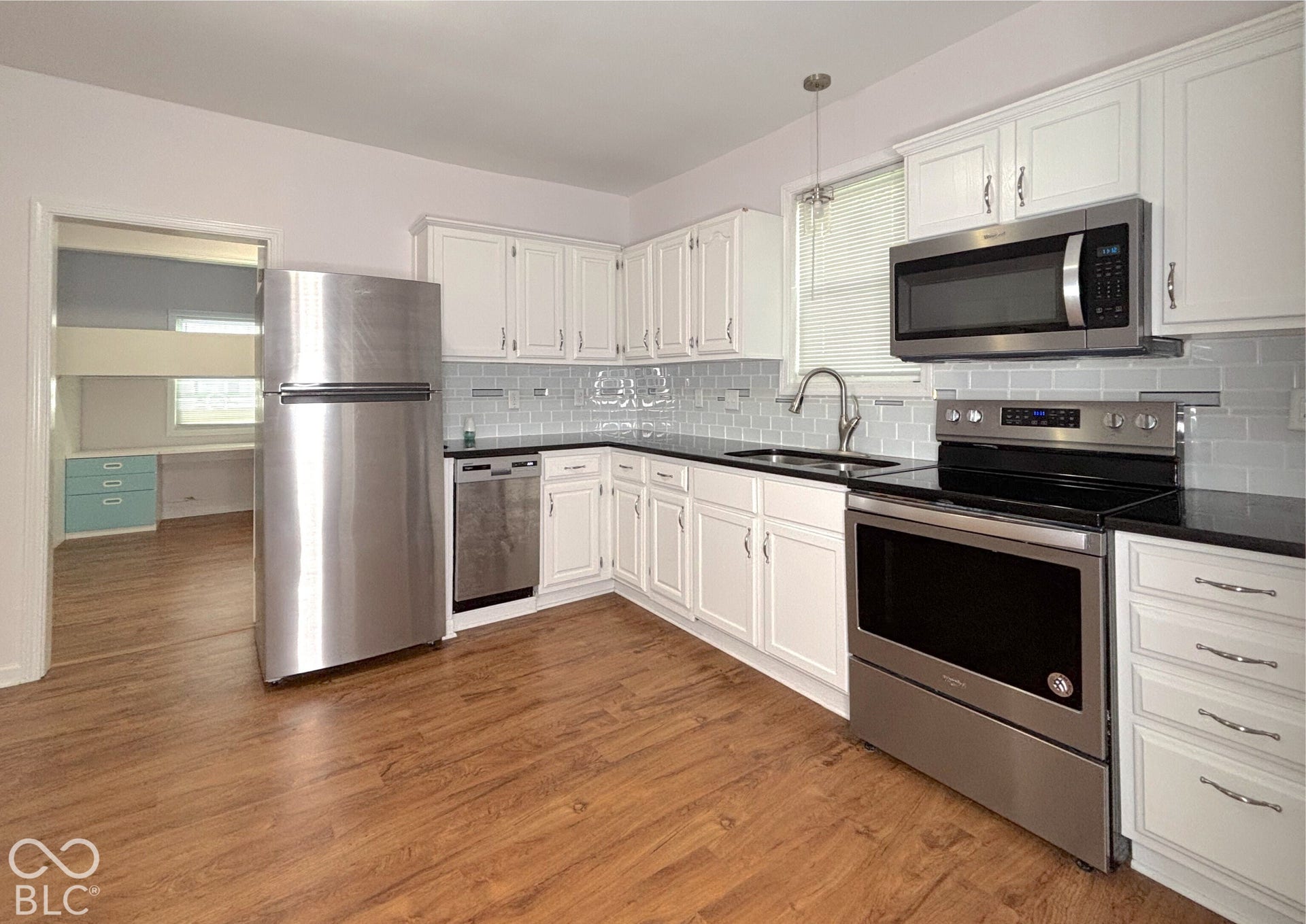 311 B Street S, Thorntown, IN 46071 White cabinetry, wood-finish flooring, stainless steel appliances, black countertops, and a gray subway tile backsplash
