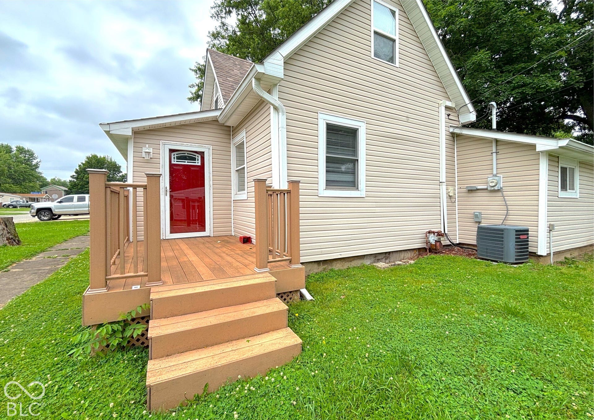 311 B Street S, Thorntown, IN 46071 Exterior featuring light-colored siding, a red entry door with decorative glass, and a raised wood-finish deck with railings