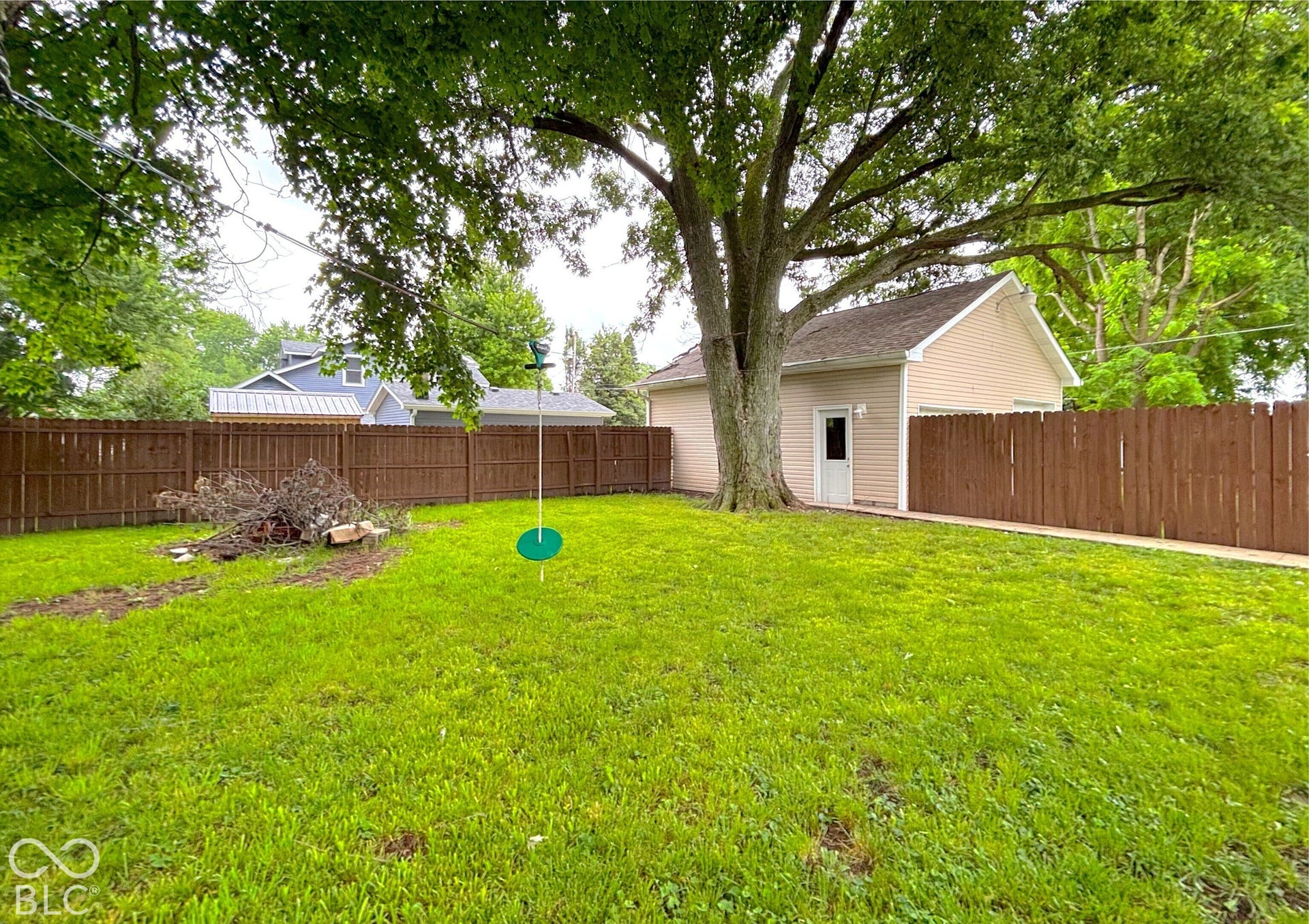 311 B Street S, Thorntown, IN 46071 Expansive grassy area featuring a mature tree, a brown privacy fence, and a detached structure with siding