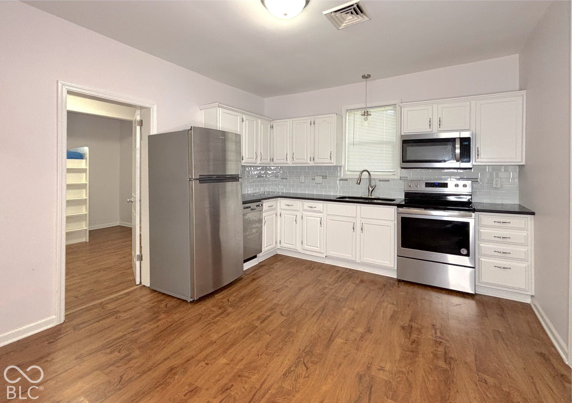 311 B Street S, Thorntown, IN 46071 Kitchen featuring white cabinetry, stainless steel appliances, dark countertops, a light gray tile backsplash, and wood-finish flooring