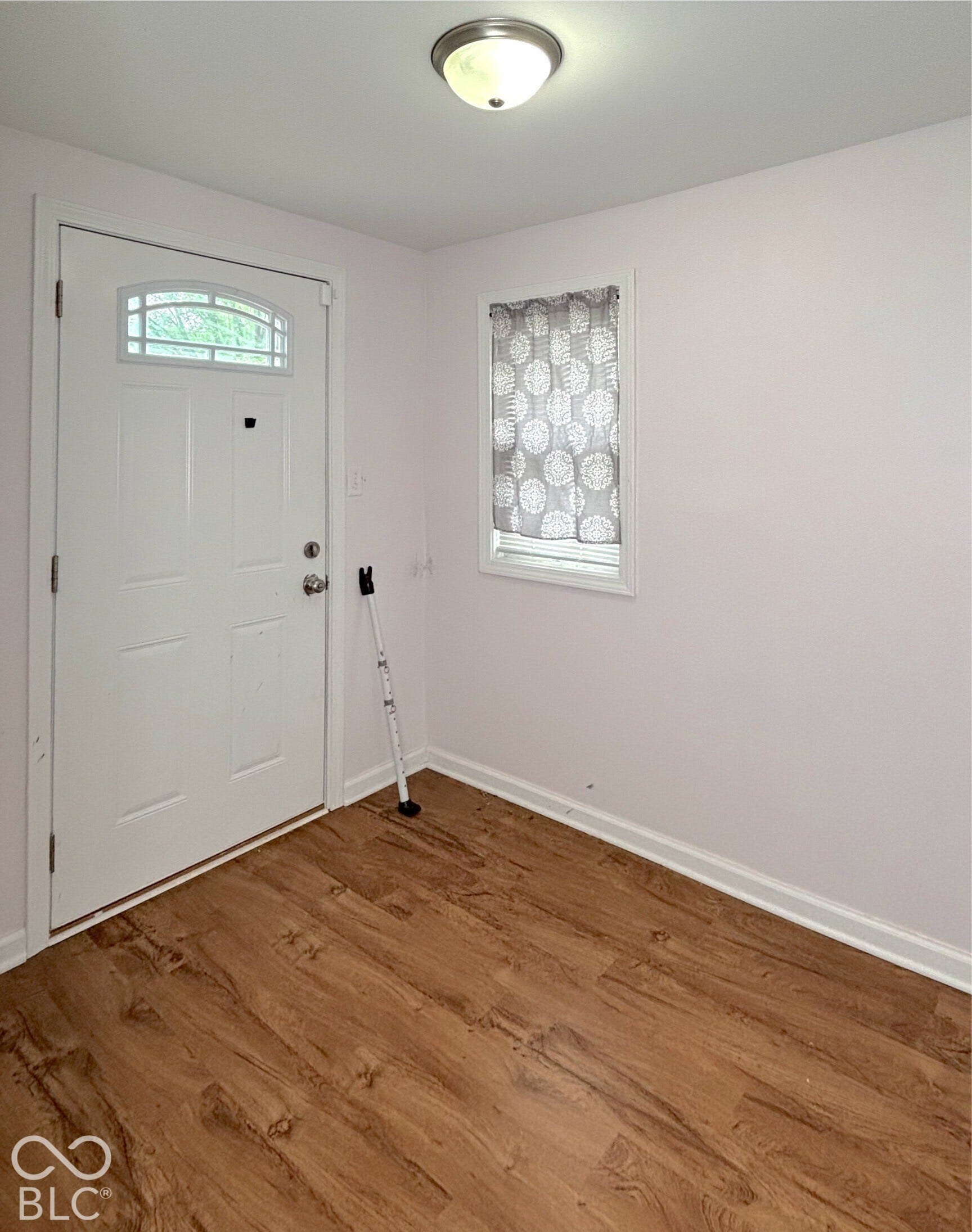 311 B Street S, Thorntown, IN 46071 Entryway featuring wood-finish flooring, a white paneled door with an arched transom, a recessed window, and a flush-mount ceiling light