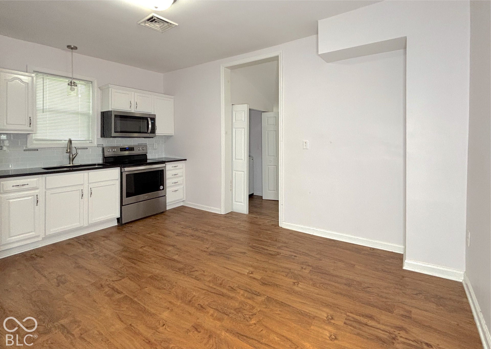311 B Street S, Thorntown, IN 46071 White cabinetry, black countertops, stainless steel appliances, white subway tile backsplash, and wood-finish flooring