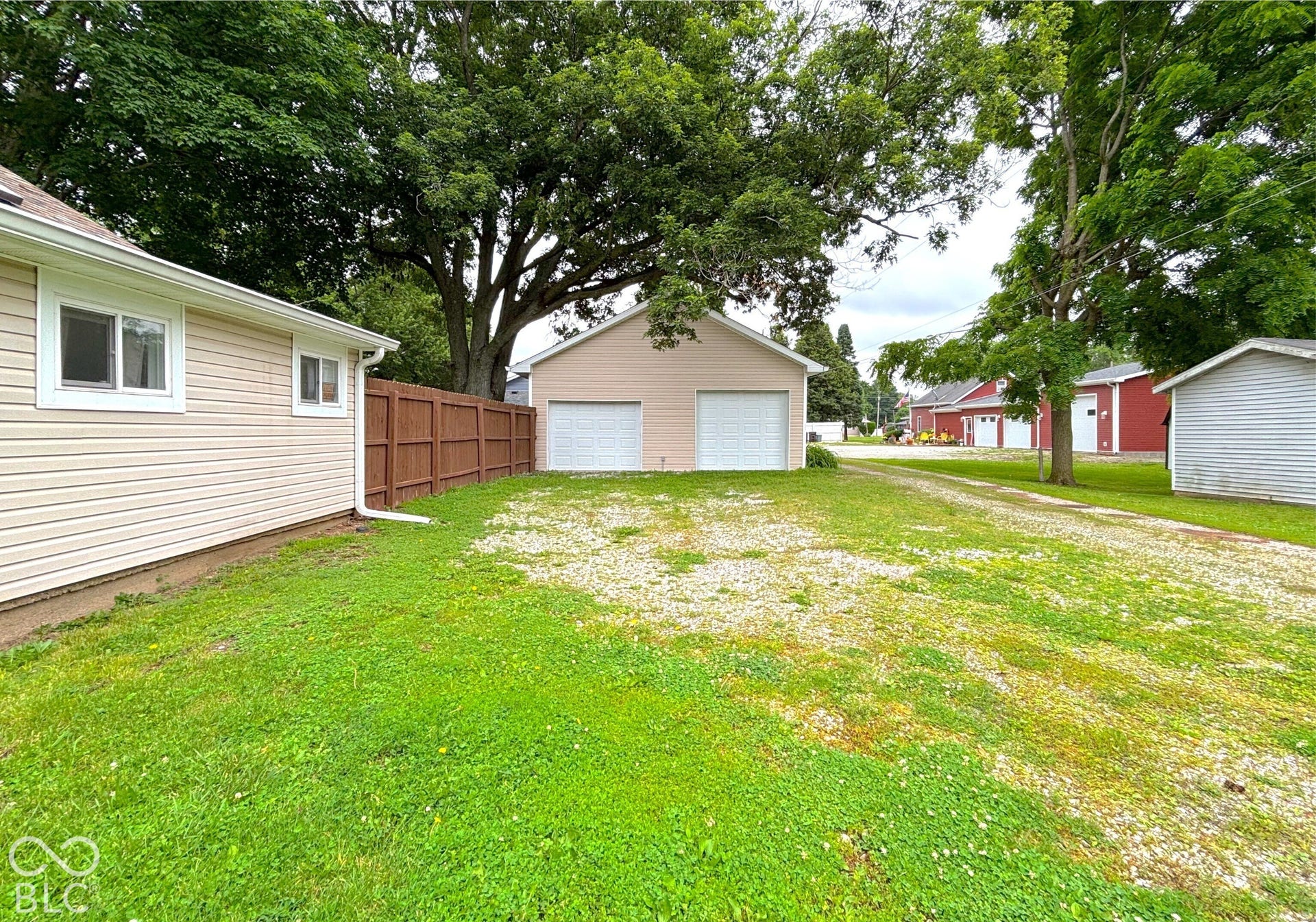 311 B Street S, Thorntown, IN 46071 Two-car detached garage with white overhead doors, gravel drive, and wood privacy fence
