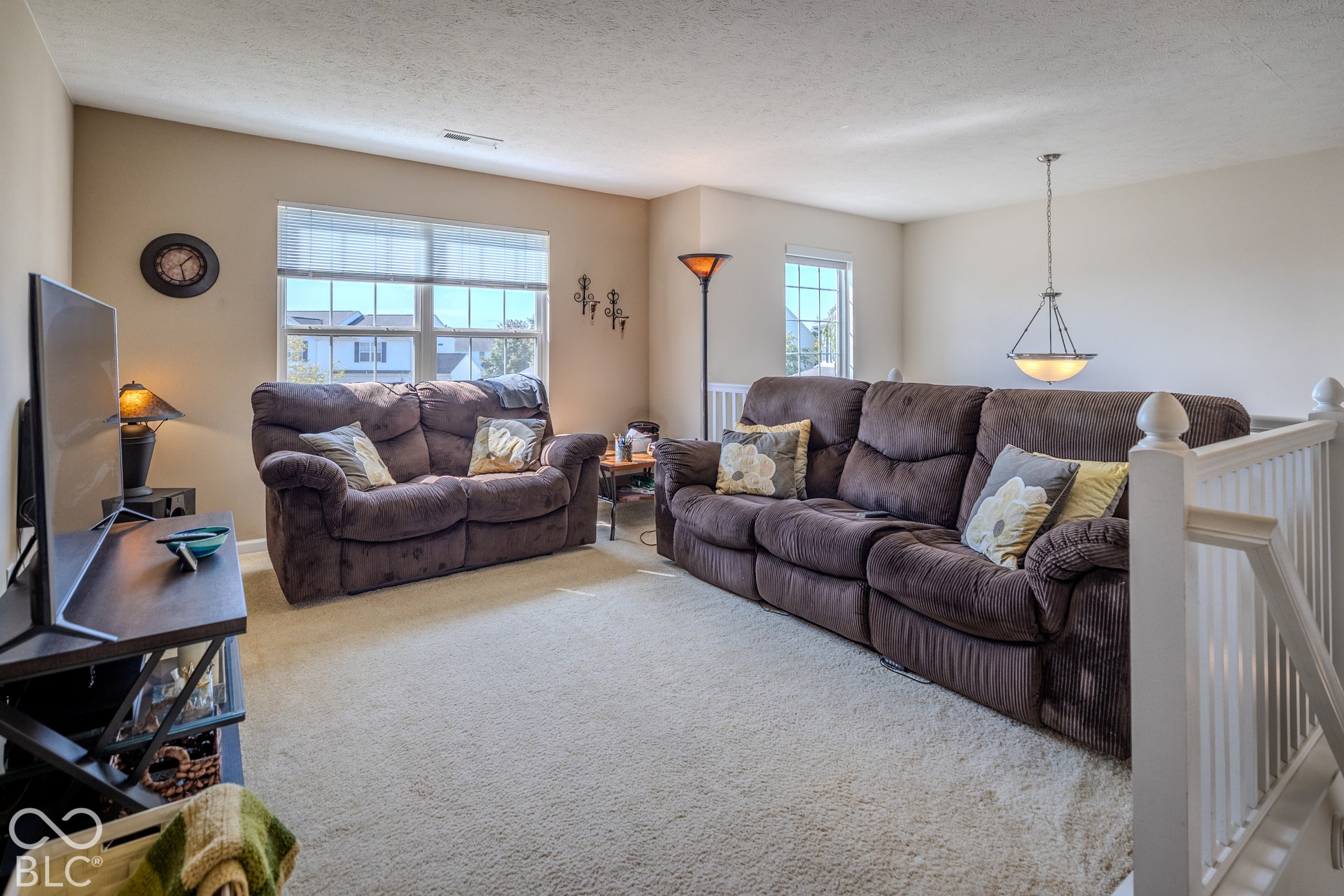 12046 Cowboys, Fishers, IN 46037 Carpeted living area with multiple windows, a ceiling-mounted light fixture, and white painted railings