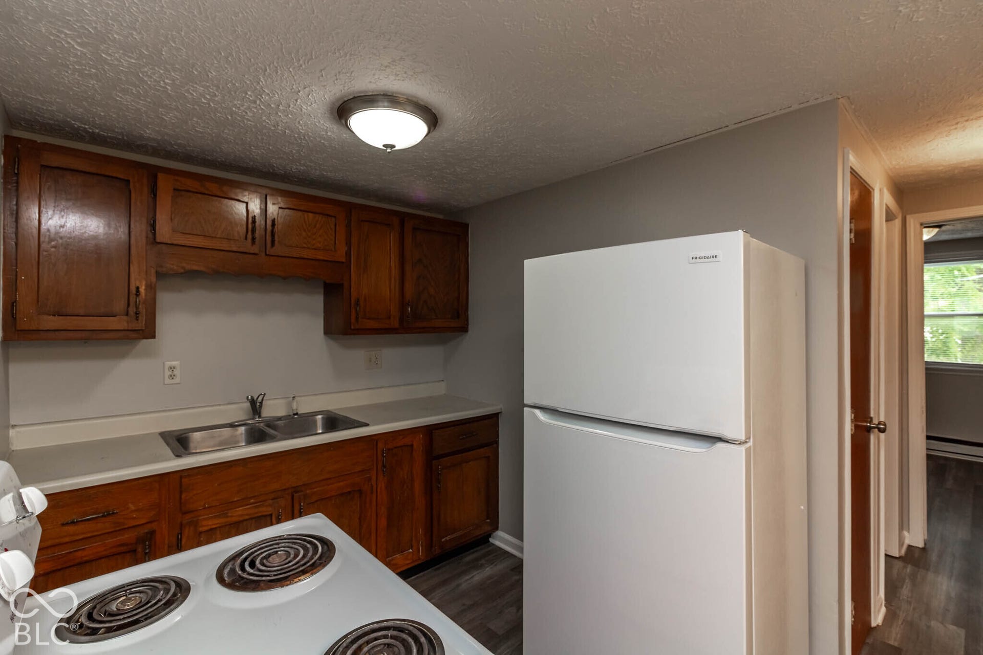 247 Apt. D Kentucky Street, Franklin, IN 46131 Kitchen featuring wood cabinetry, a dual basin stainless steel sink, and a white refrigerator