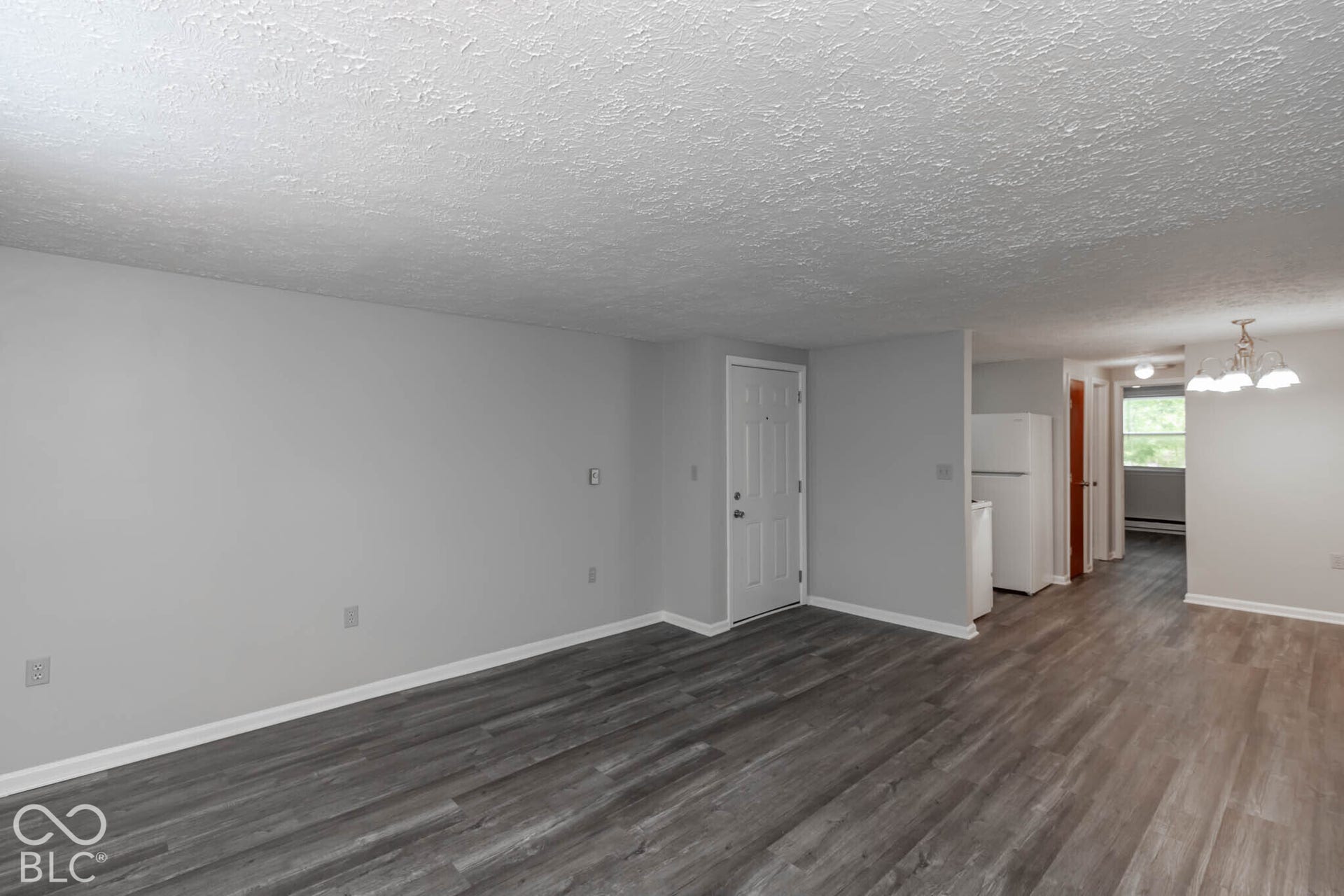 247 Apt. D Kentucky Street, Franklin, IN 46131 Open-concept living space featuring wood-finish flooring, light gray wall paint, white trim, and a white entry door