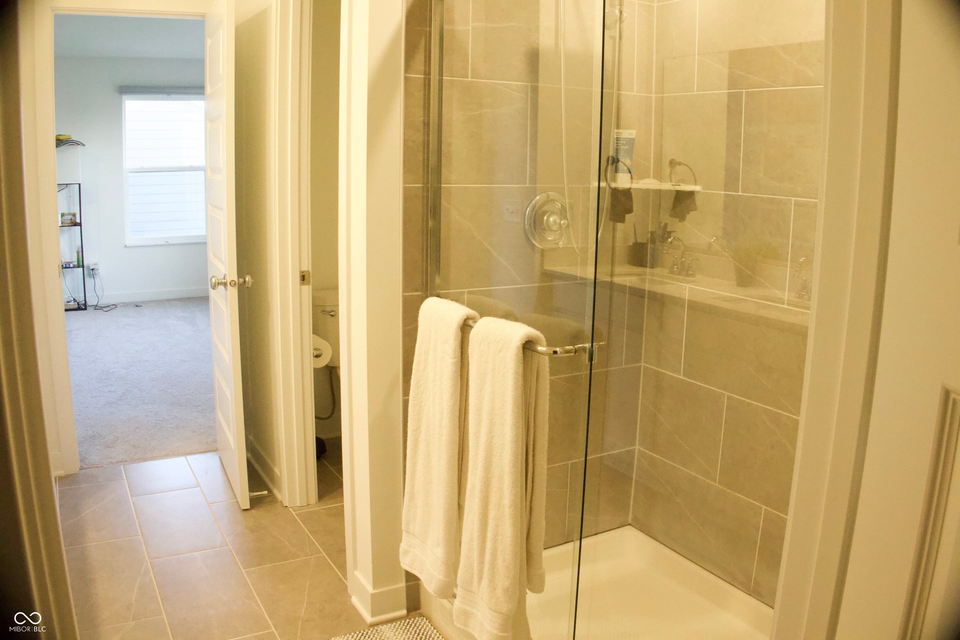 Glass-enclosed shower with full-height tile surround, integrated shelving, and a built-in shower bench