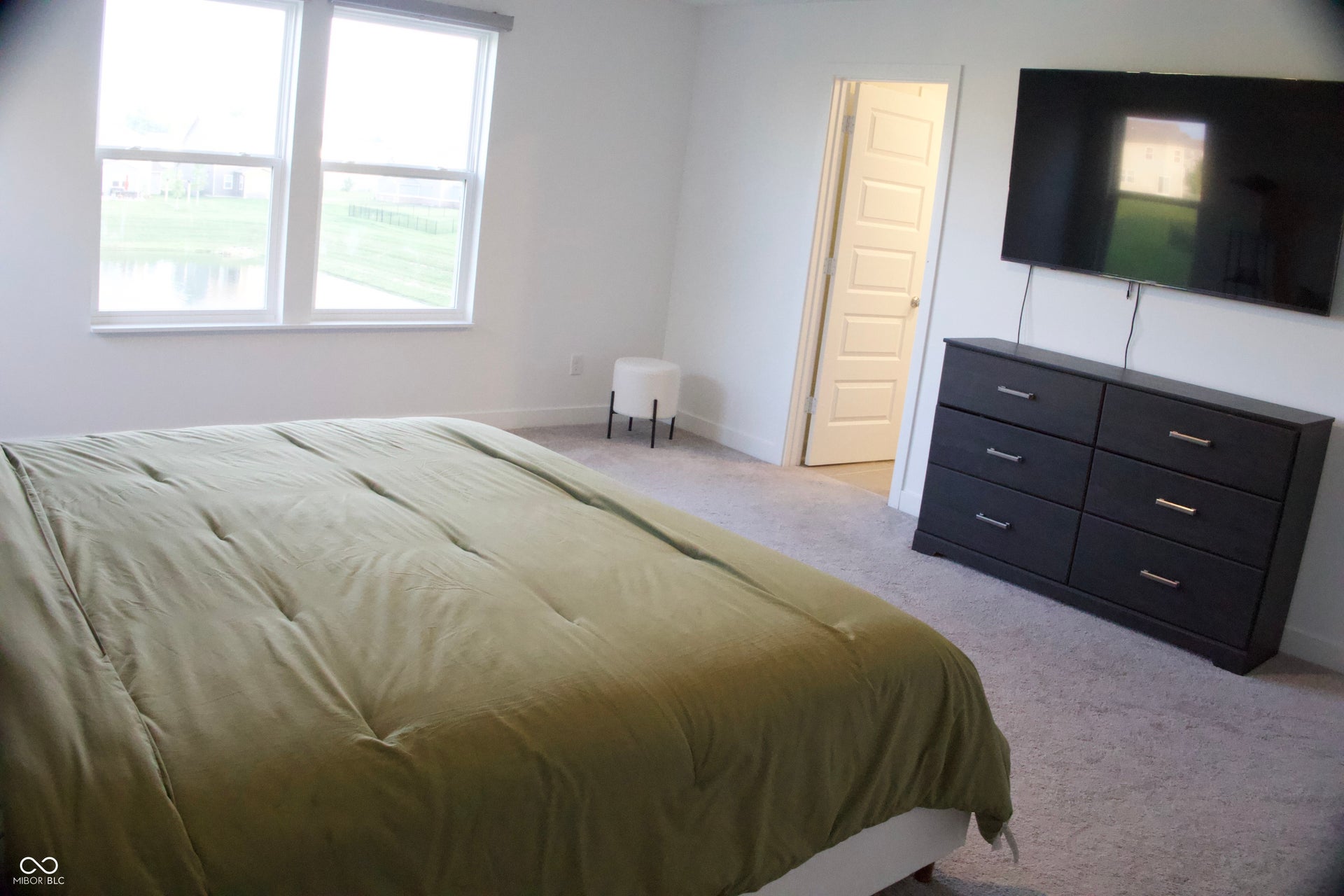 Spacious bedroom featuring light-toned carpeting and bright white walls