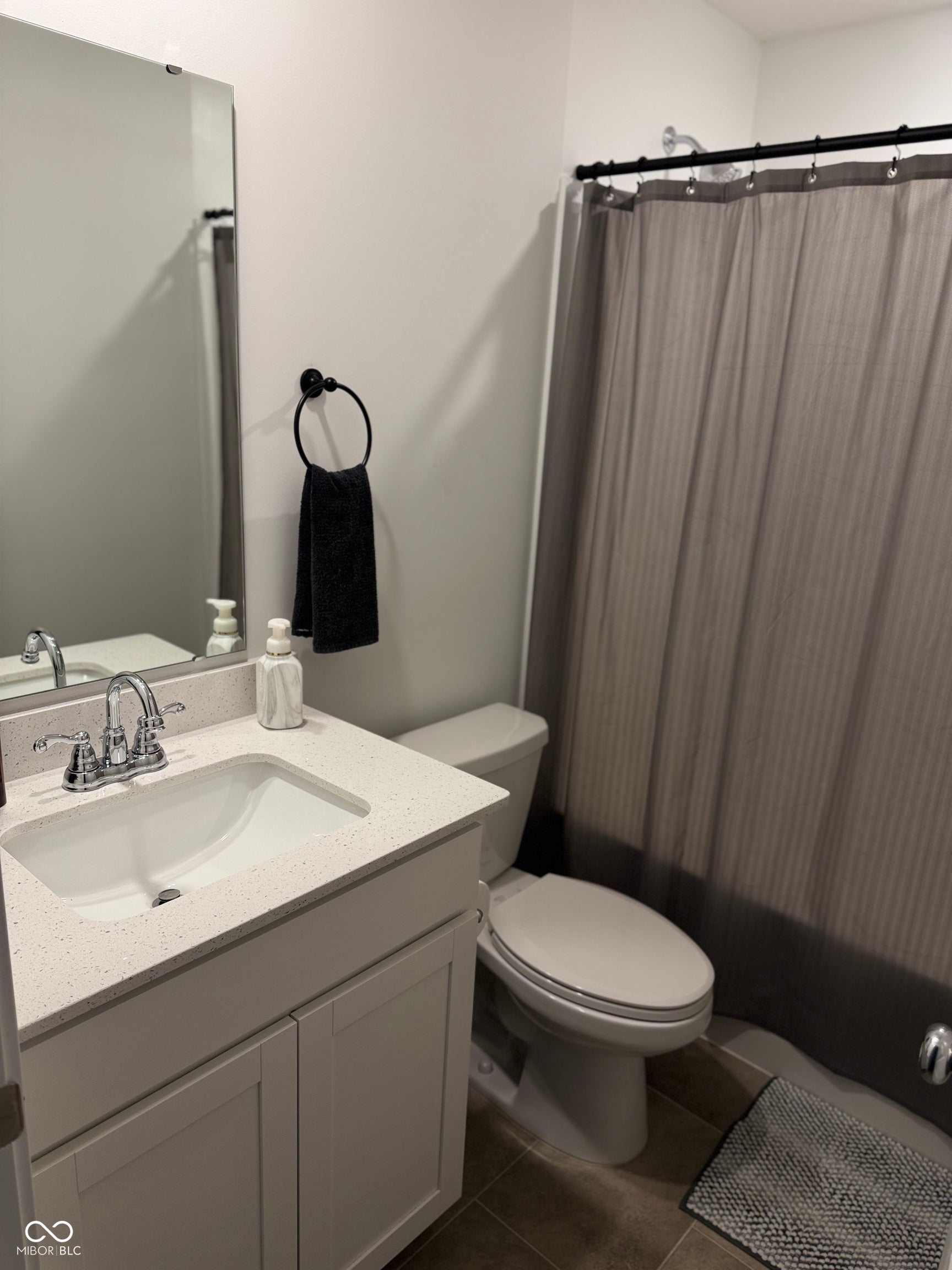 Bathroom featuring a white vanity with a speckled countertop, undermount sink, chrome faucet, and a wall-mounted mirror